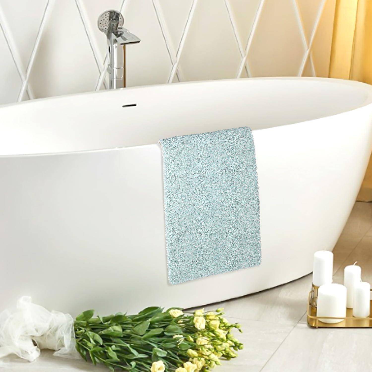 Moderne freistehende weiße Badewanne mit Duschkopf, drapiertes hellblaues Handtuch und Blumen daneben in einem hellen Badezimmer