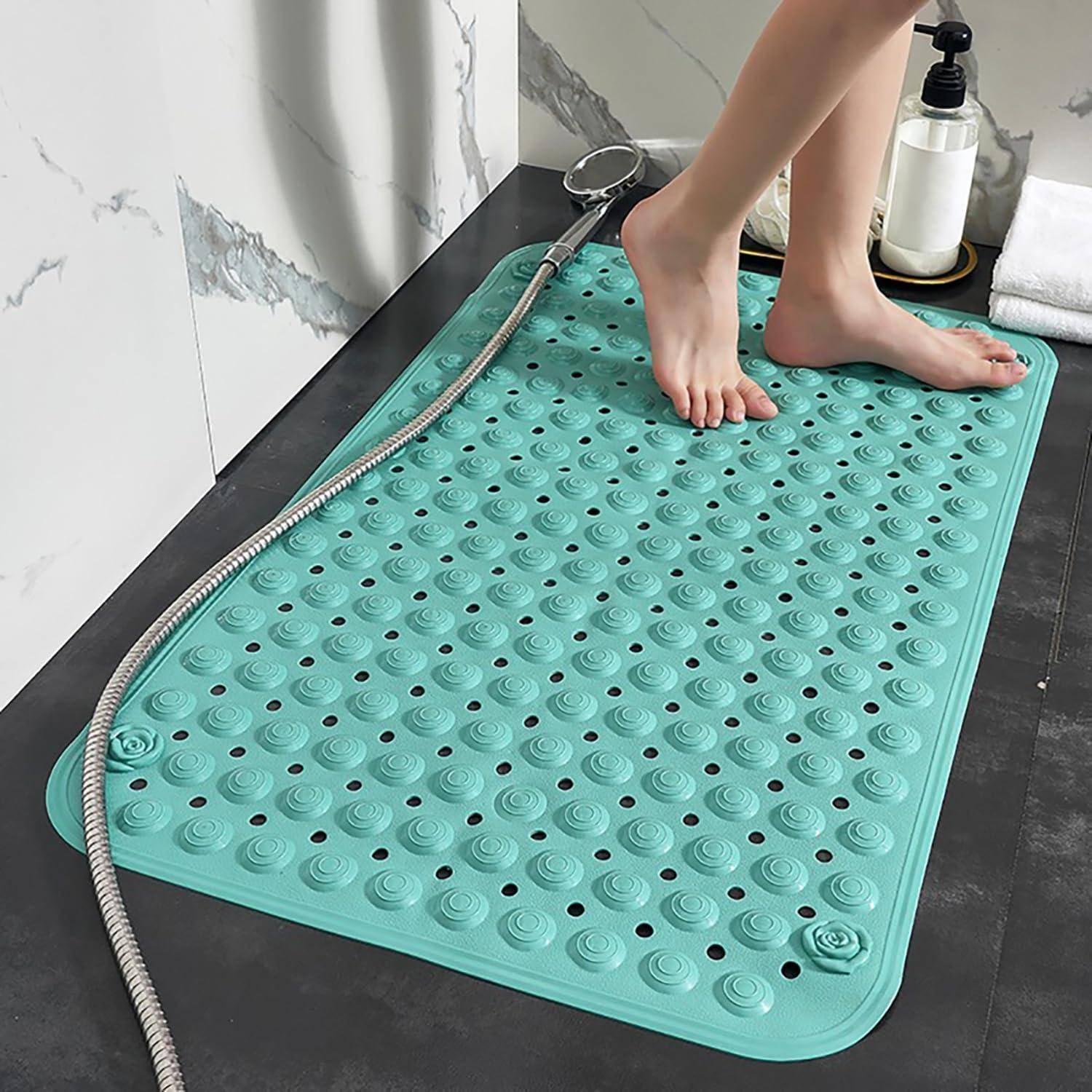 Nackte Füße stehen auf einer türkisfarbenen strukturierten Badmatte in einer Dusche, mit einem Schlauch und einem Seifenspender in der Nähe.