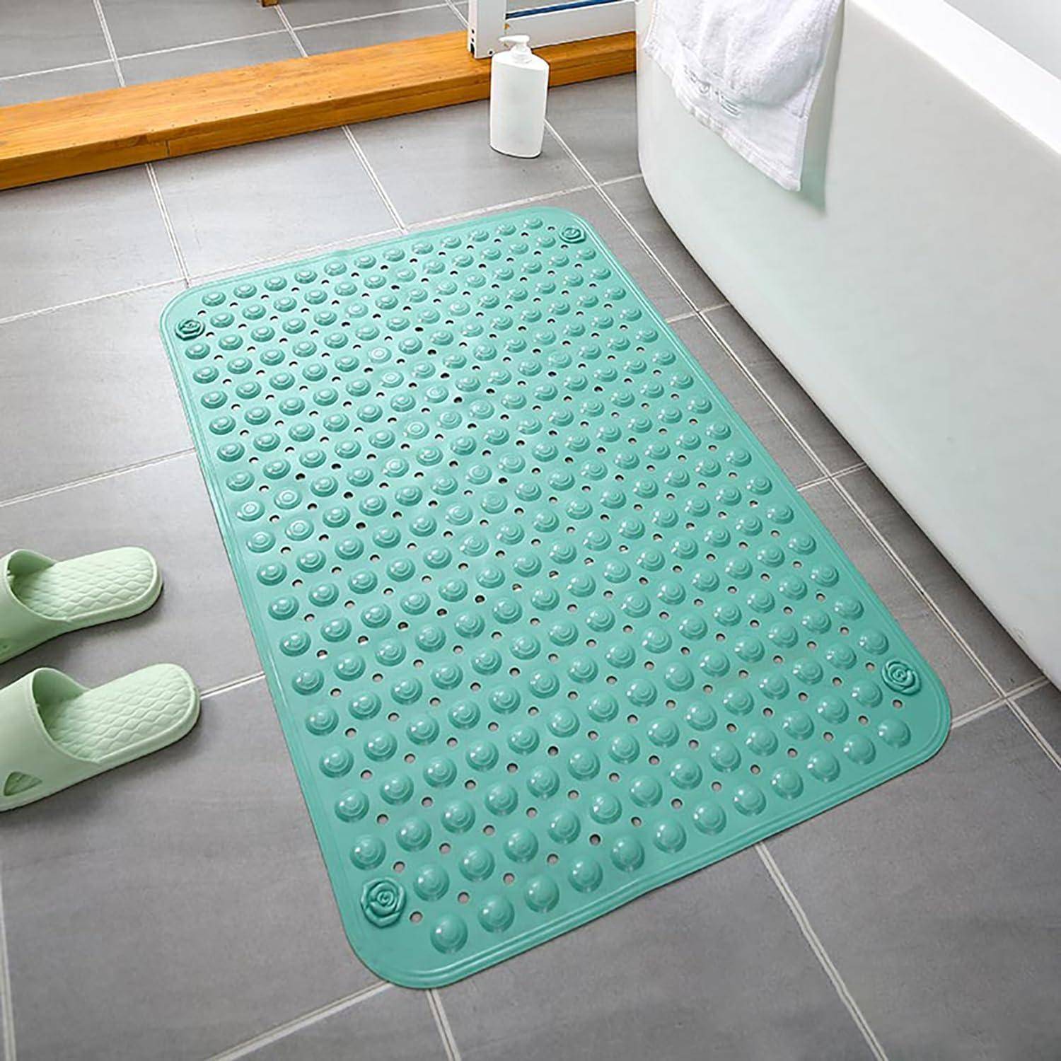Türkisefarbene rutschfeste Badezimmermatte mit erhabenen Saugnapfbeulen auf einem gefliesten Badezimmerboden neben einer Badewanne und Pantoffeln.