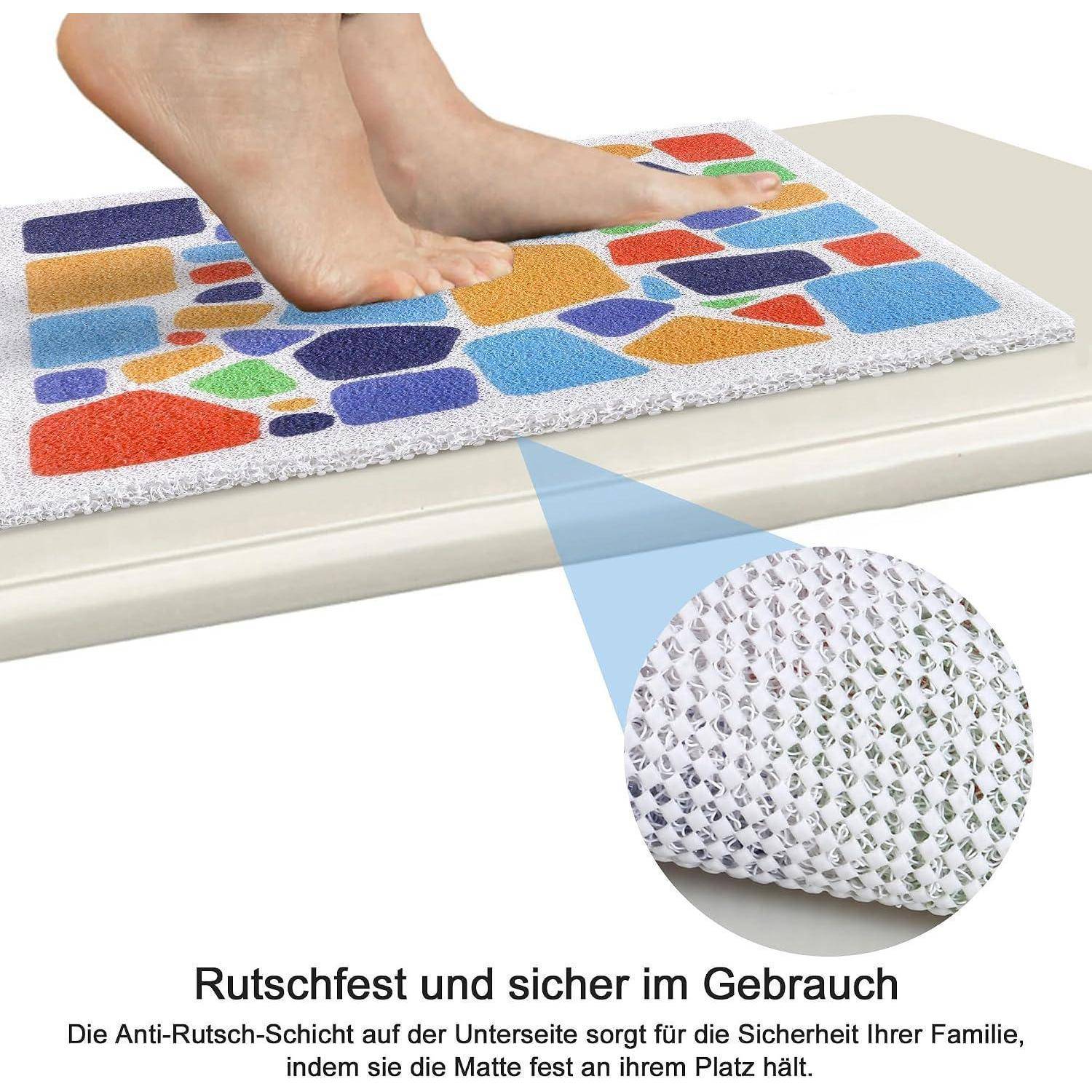 Füße stehen auf einer farbenfrohen Badematte mit rutschfester Unterseite in Nahaufnahme; deutscher Text sagt „Rutschfest und sicher in der Anwendung