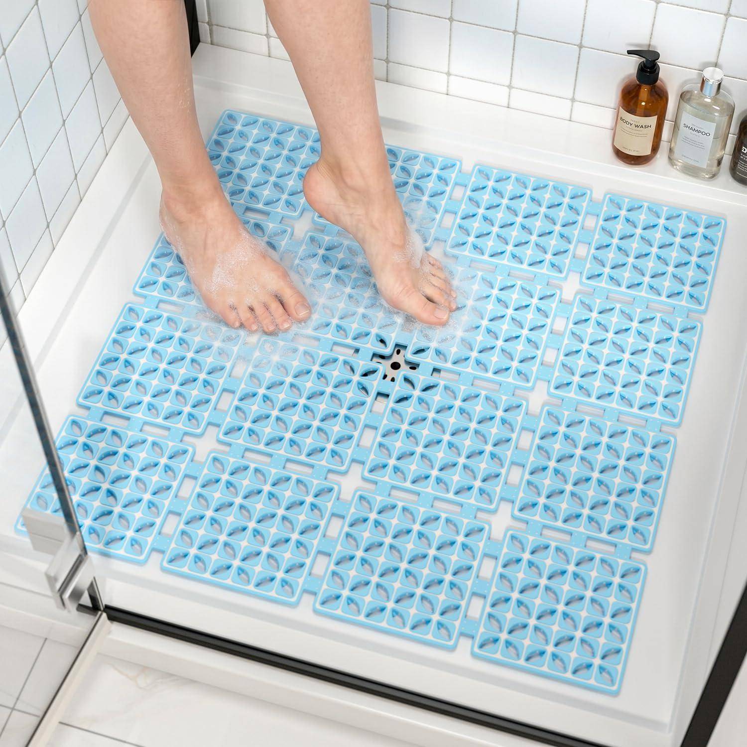 Nackte Füße stehen auf einer blauen rutschfesten Badematte in einer gefliesten begehbaren Dusche.