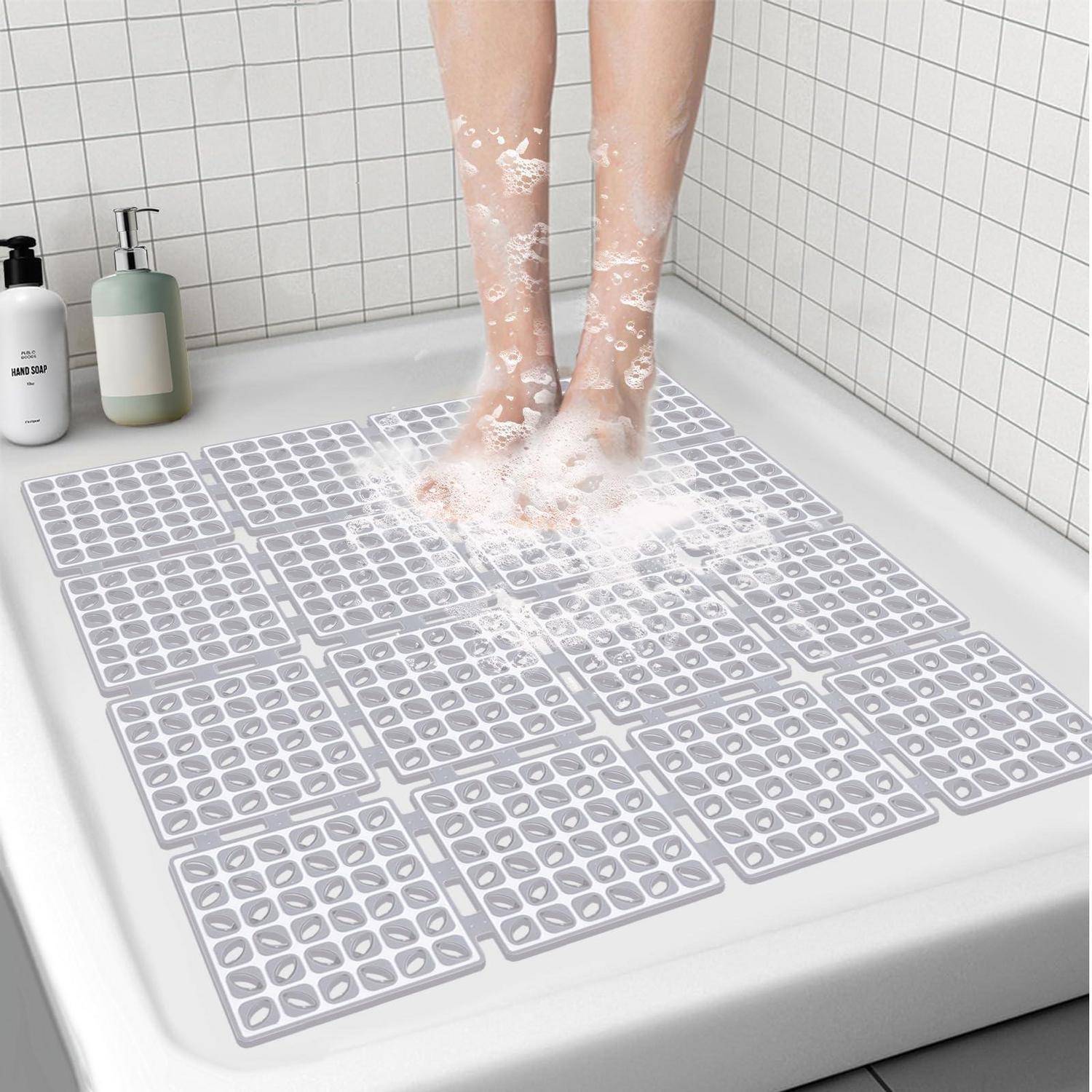 Person, die in einer Dusche steht und mehrere rutschfeste Badematten auf dem Boden benutzt, mit Seifenflaschen in der Nähe.