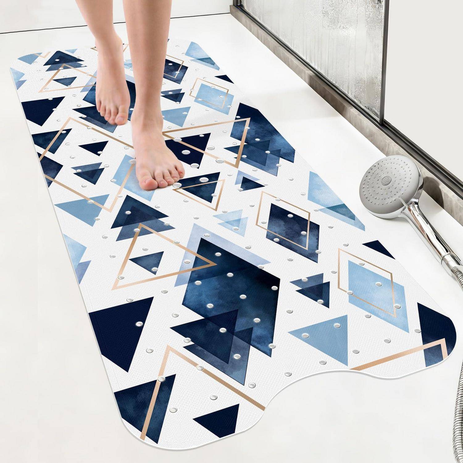 Nackte Füße, die auf einer geometrischen rutschfesten Badmatte neben einem Duschkopf in einem Badezimmer stehen.