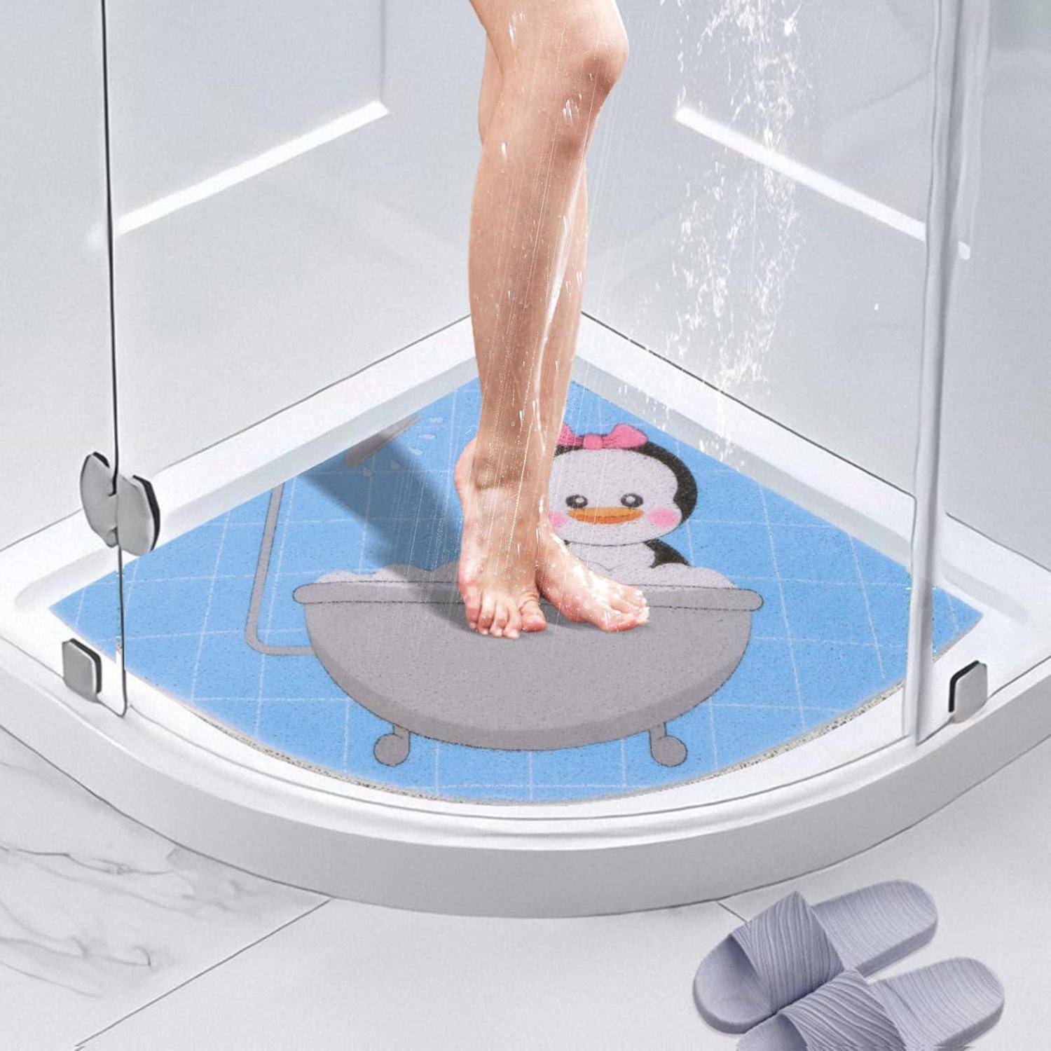 Person, der in einer Eckendusche mit Glasumrandung steht, unter den Füßen eine blaue Pinguin-Badezimatte.
