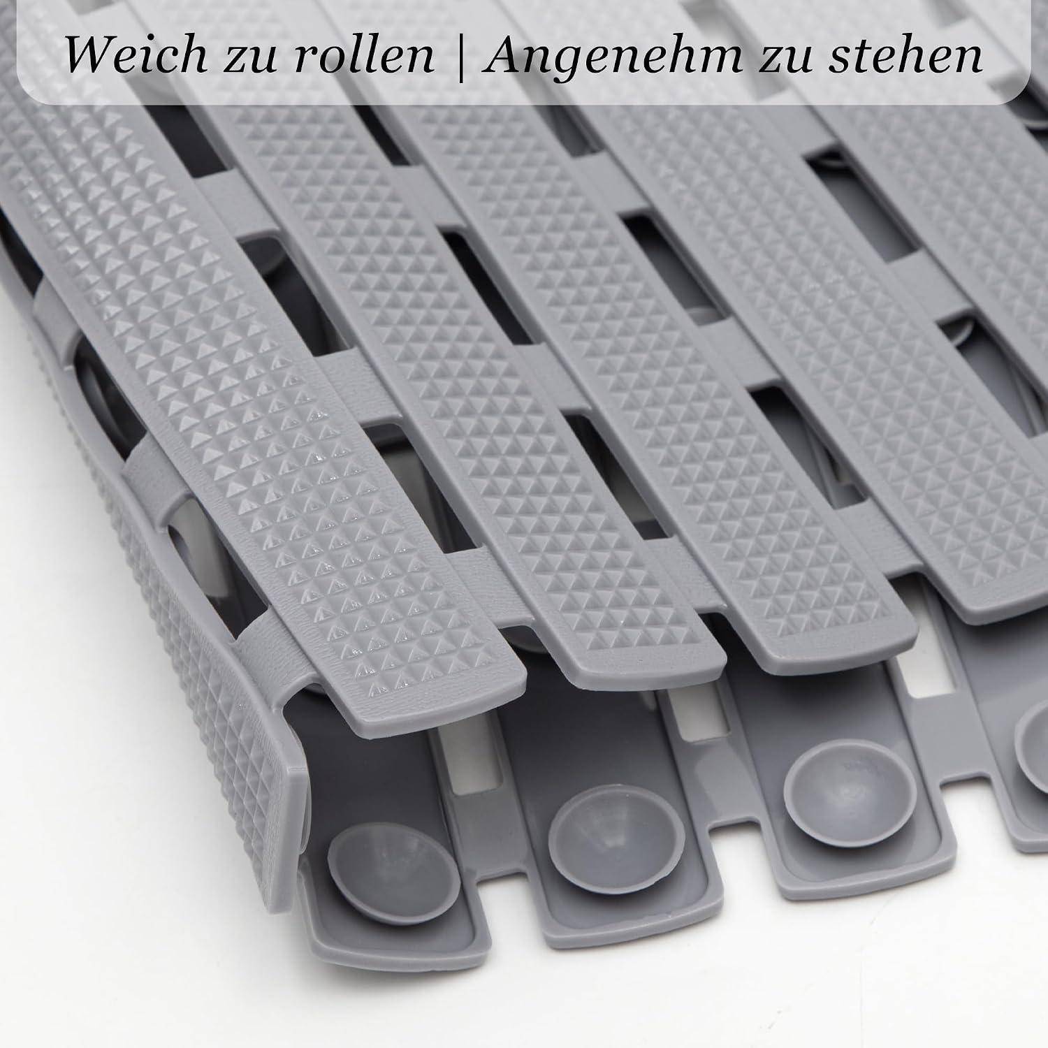 Nahaufnahme von grauer, strukturierter Klettverschluss-ähnlicher Schuhwickel oder Riemen, die übereinander ausgelegt sind, mit deutschem Text „Weich zu rollen | Angenehm zu stehen