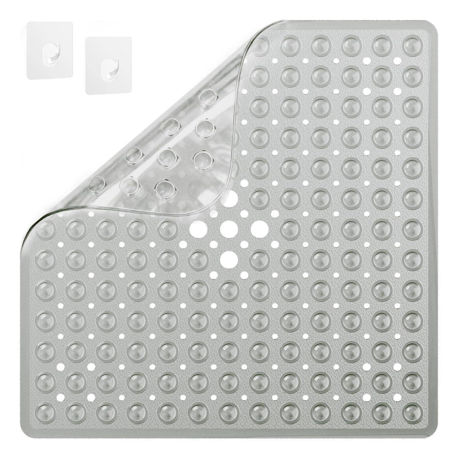 Transparente quadratische Silikonmatte mit Saugnapf, erhabenen Punkten und umgeklappter Ecke, dargestellt mit zwei kleinen Wandhaken-Pads.