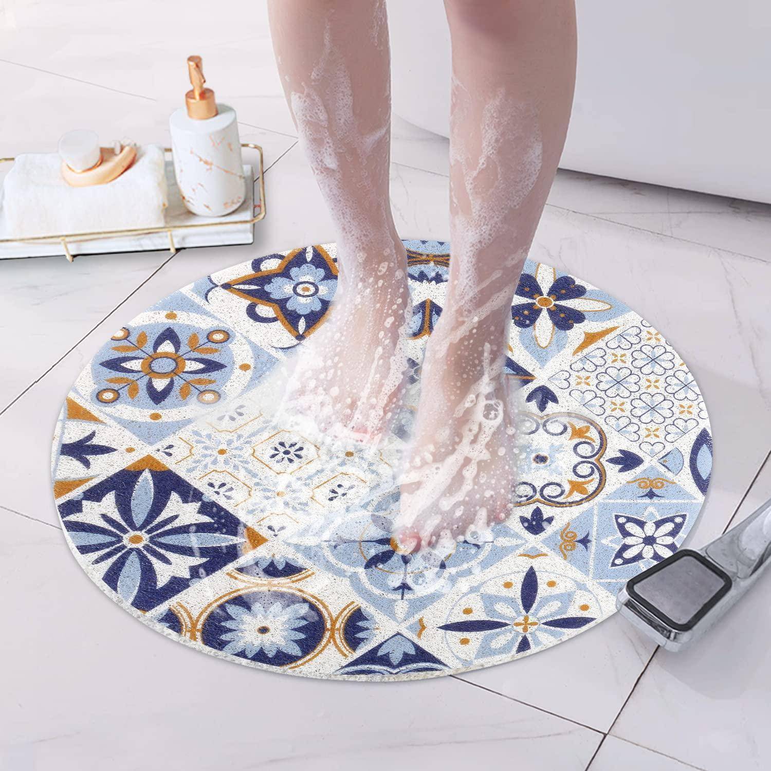 Füße, die auf einer runden gemusterten Badematte duschen, mit Wasser, das über die mosaikähnliche Oberfläche auf einem gefliesten Badezimmerboden spritzt.