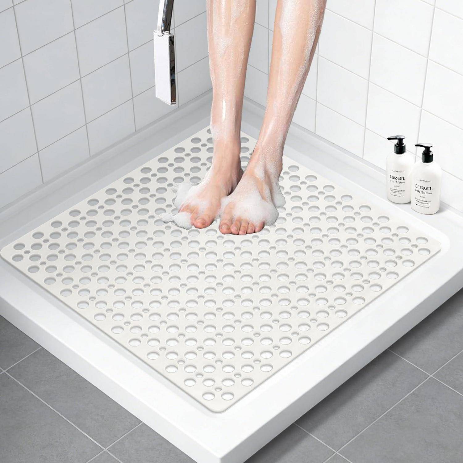 Person duscht in einer begehbaren Dusche mit weißen Fliesen, eine strukturierte Anti-Rutsch-Badewannenmatte auf dem Boden und Seifenflaschen auf dem Regal.