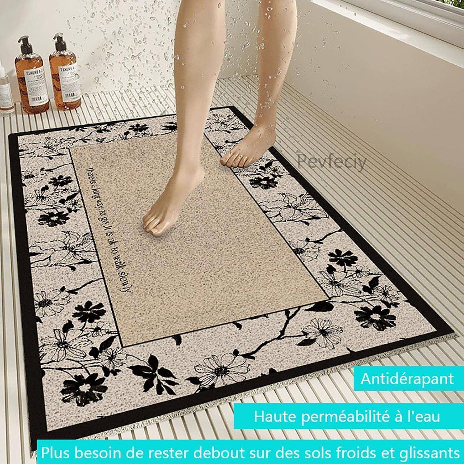 Rutschfeste Badmatte mit Blumenrand, gezeigt in einem Badezimmer unter nassen Füßen; französischer Text hebt hohe Wasserdurchlässigkeit und die Notwendigkeit hervor, nicht auf kalten, rutschigen Böden zu stehen.