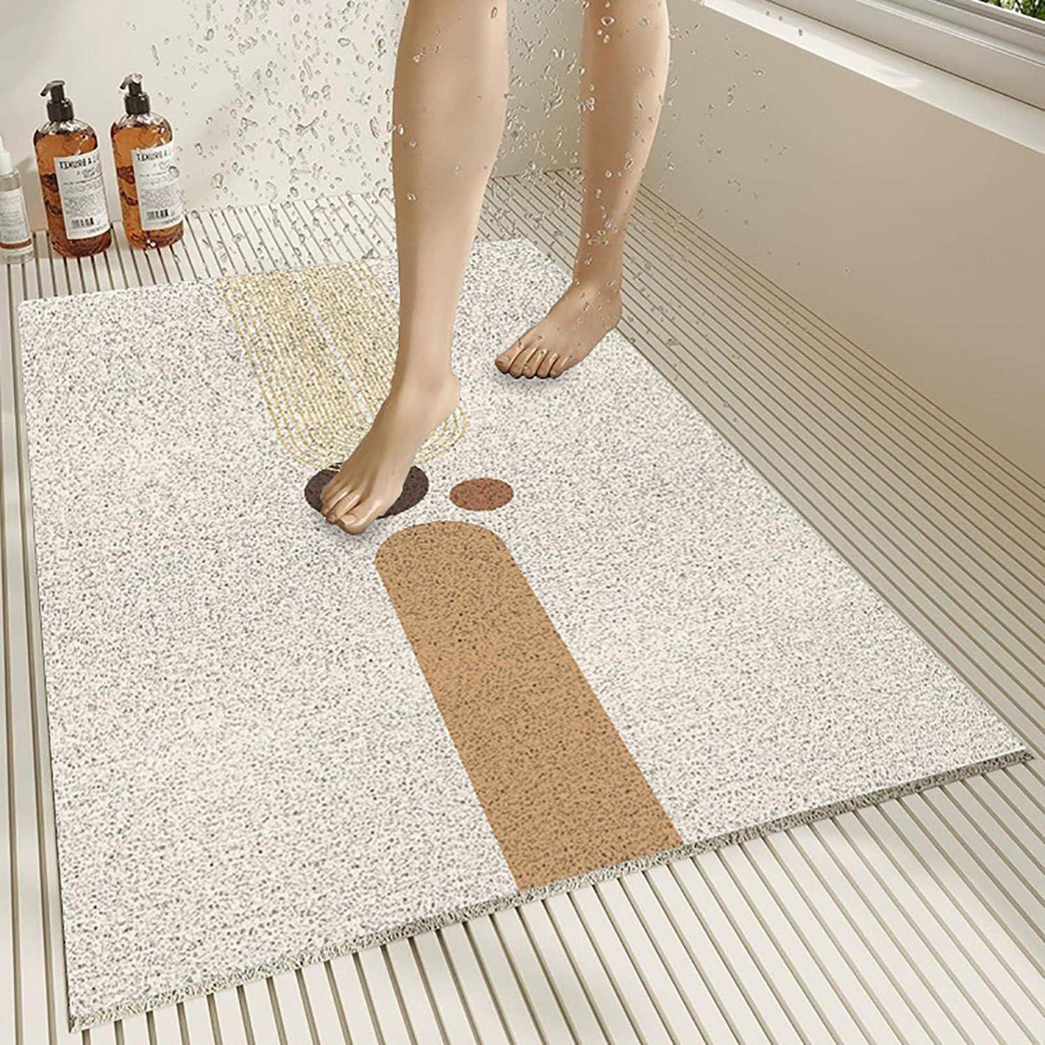Person steht auf einer strukturierten Badezimmermatte mit einem einfachen Gesichtsdesign, neben zwei Flaschen auf dem Boden neben einer Badewanne.