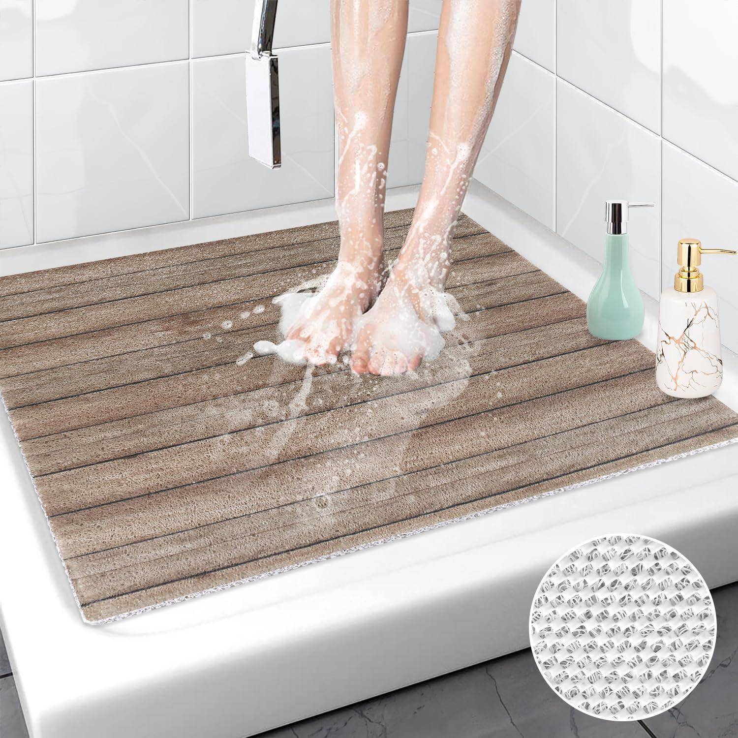 Füße stehen auf einer strukturierten Badmatte in einer Dusche, mit Wasser, das auf die saugfähige Matte spritzt, und Badezimmerfläschchen in der Nähe.