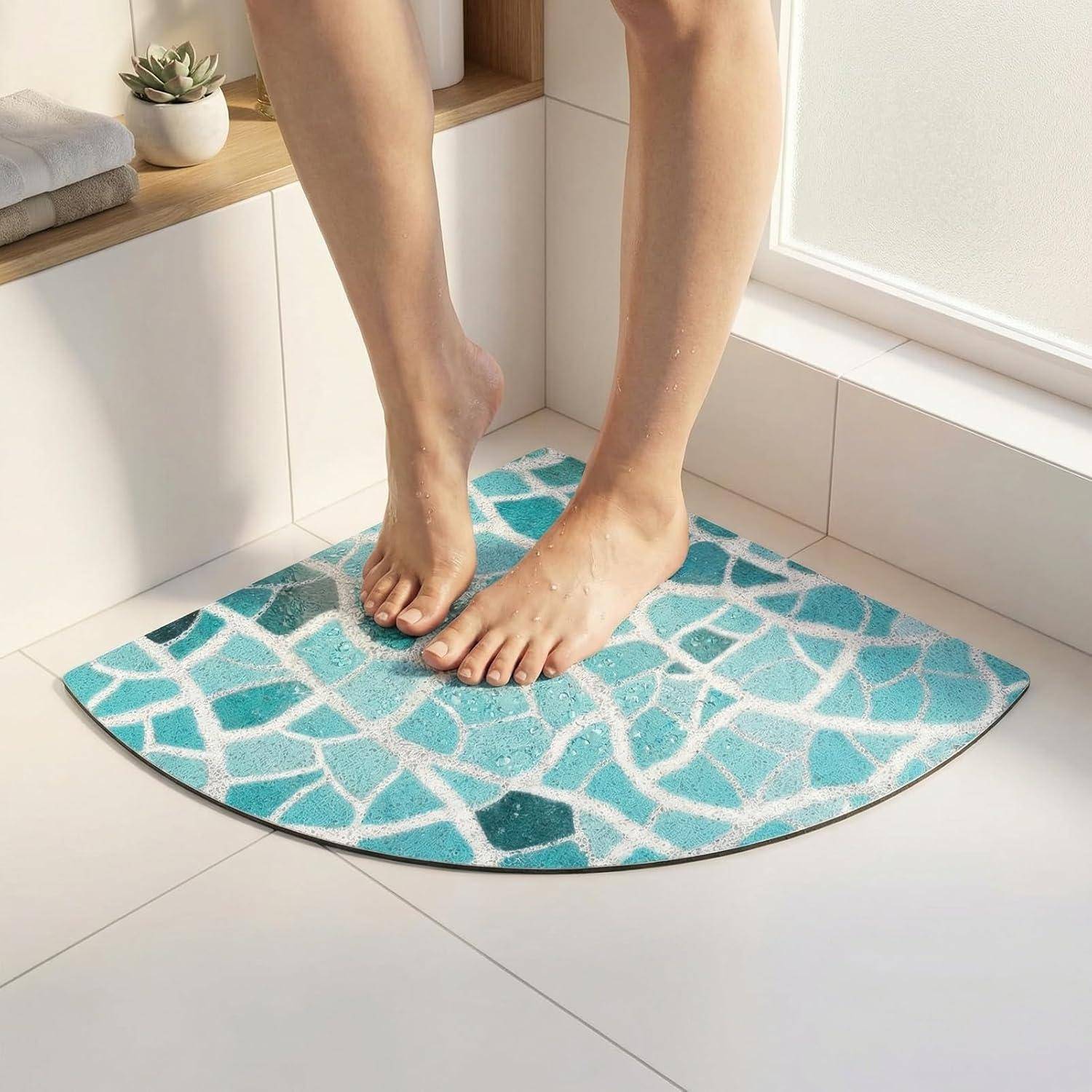 Nackte Füße stehen auf einer blauen, gemusterten Badeteppich in einem hellen Badezimmer neben einem Fenster.
