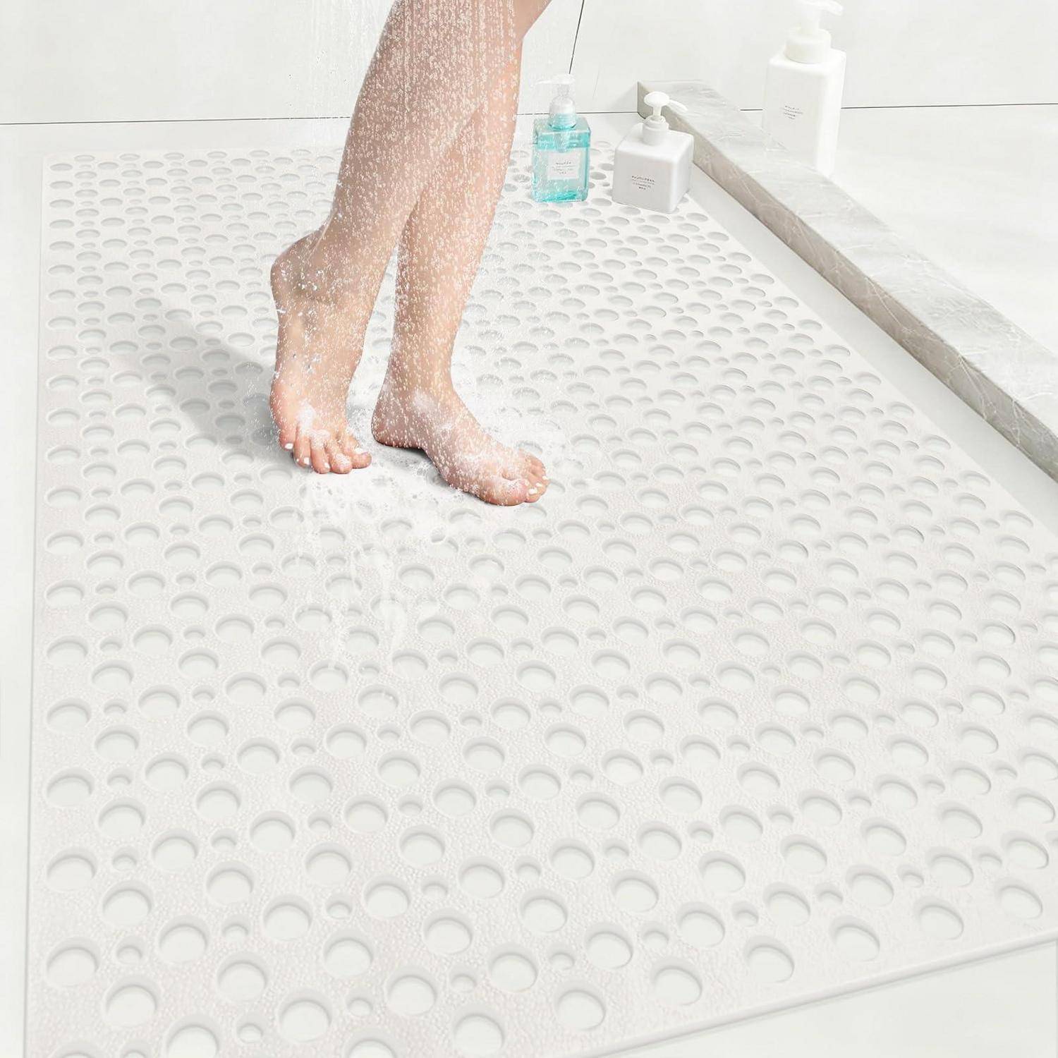 Person wäscht sich die unteren Beine unter der Dusche, während Wasser über eine weiße Anti-Rutsch-Duschmatte läuft.