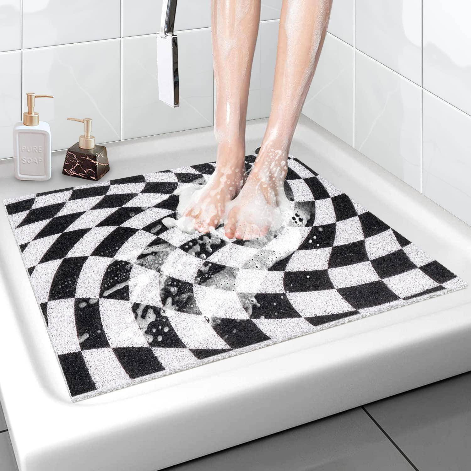 Person, die nackte Füße in einer Dusche auf einer schwarzweißen karierten Badematte mit Seifenblasen wäscht.