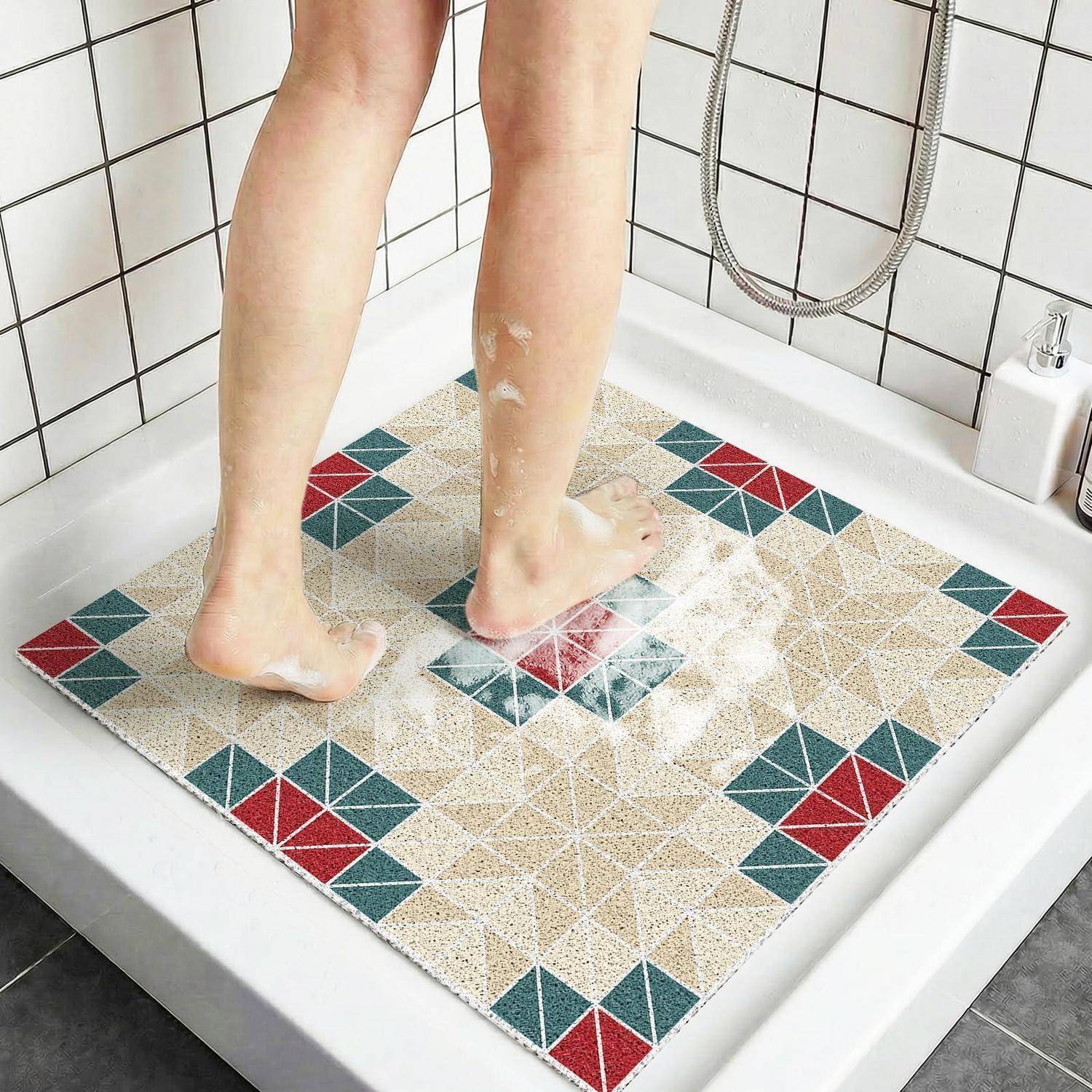 Person duscht auf einer geometrischen Mosaikmuster-Matte in einer weißen Duschkabine mit gefliesten Wänden und einem sichtbaren tragbaren Duschkopf.