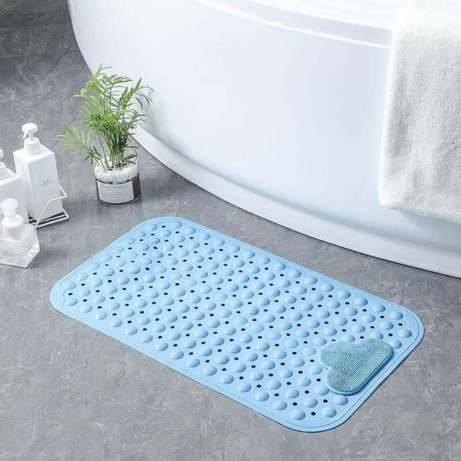 Hellblaue rutschfeste Badmatte mit erhabenen Kreisen und einem kleinen strukturierten Reinigungspad neben einer Badewanne auf grauem Boden.