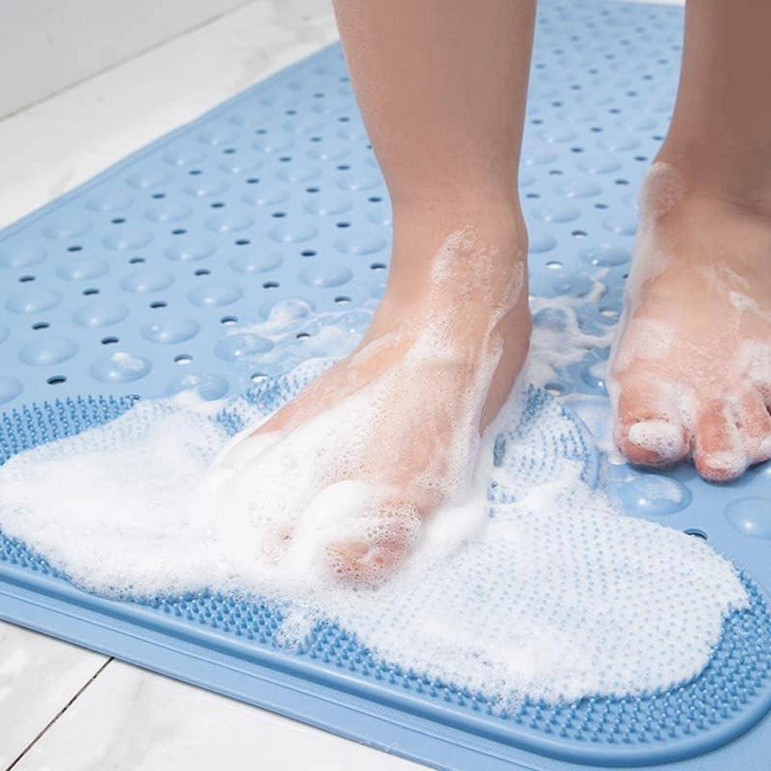 Füße werden auf einer blauen strukturierten Badmatte, die mit Seifenschaum bedeckt ist, geschrubbt.