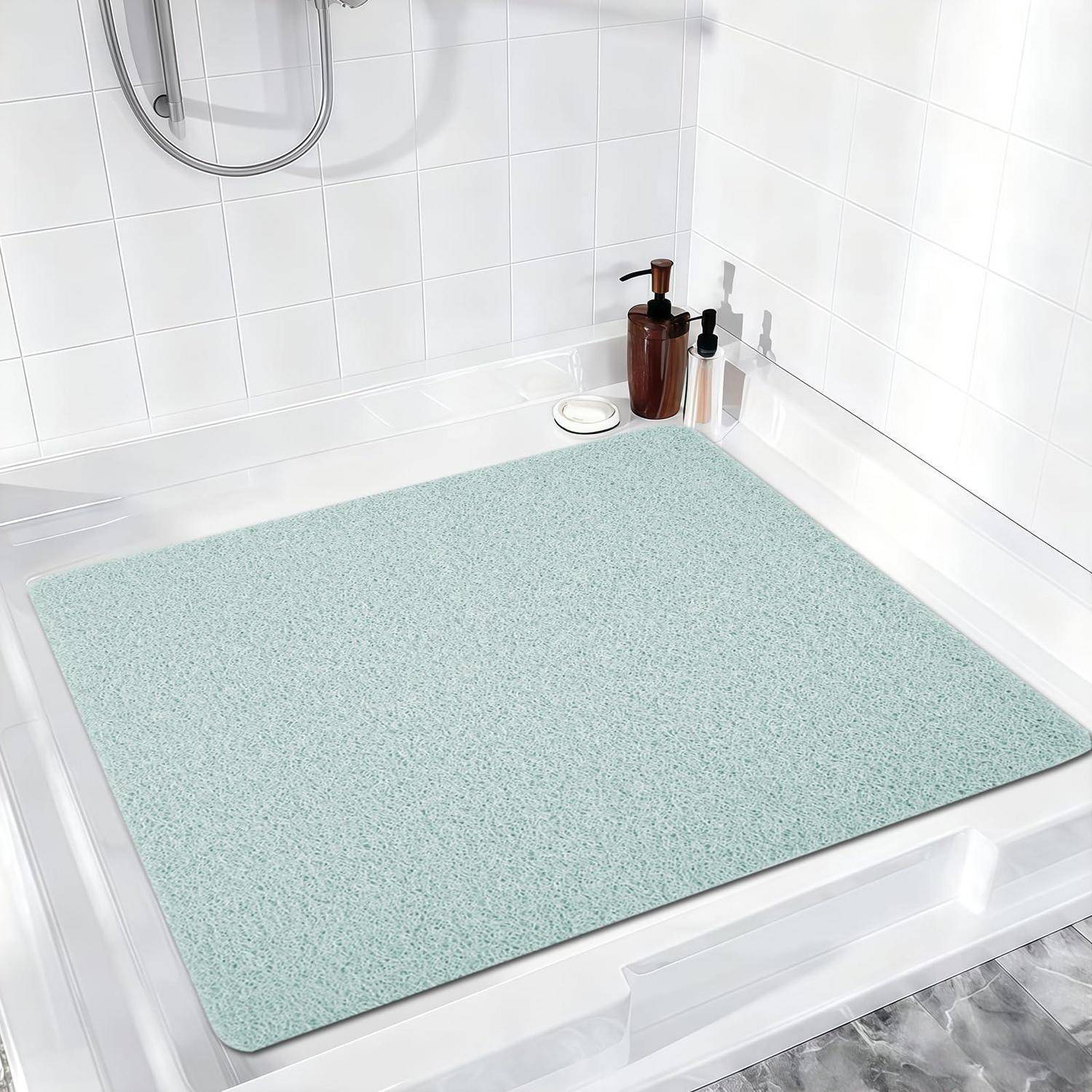 Eine hellgrüne Badematte füllt eine weiße Badewanne, mit Seifenspendern auf dem Eckregal in einem hell gefliesten Badezimmer.