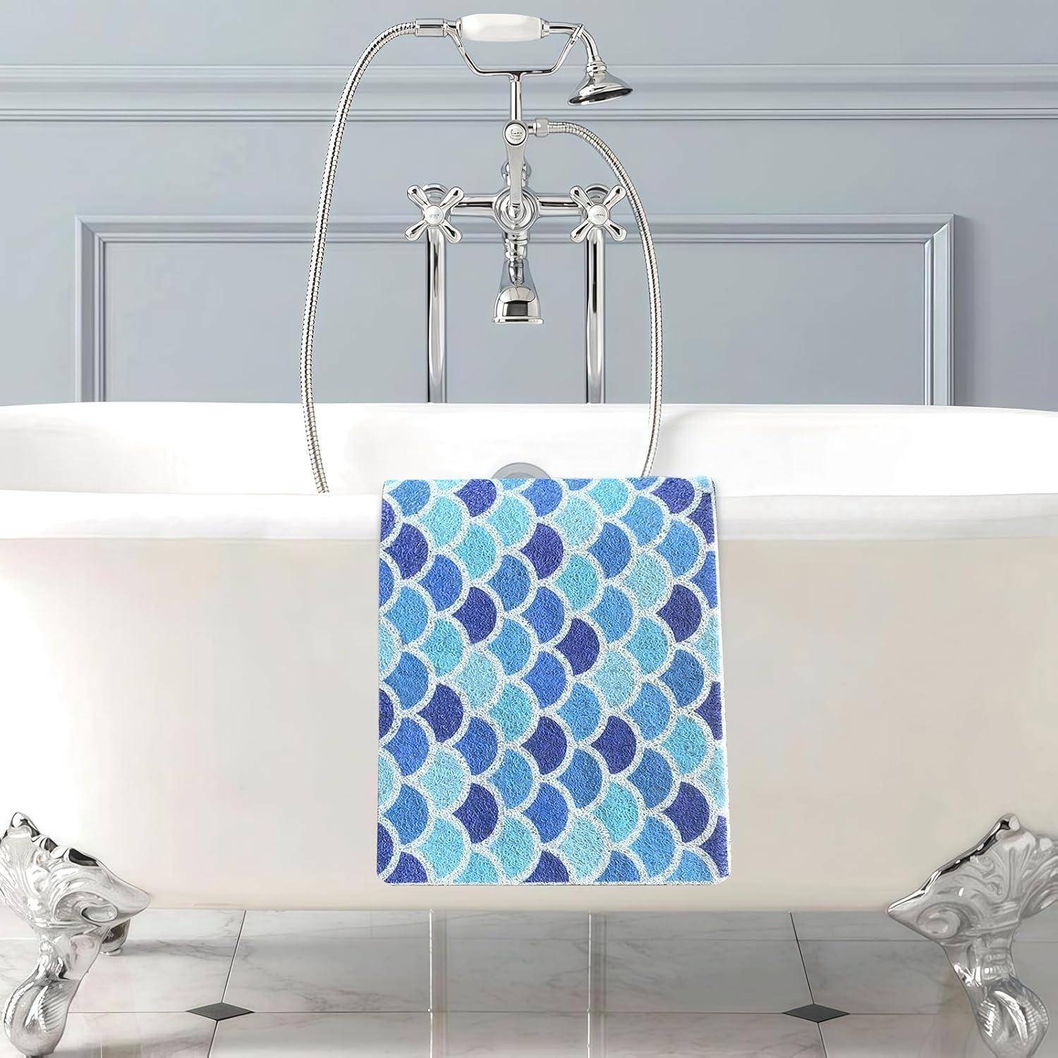 Weiße Badewanne mit Klauentüßen und verchromtem Wasserhahn und blauem Fischgrät-Handtuch, das über der Vorderseite in einem gefliesten Badezimmer drapiert ist