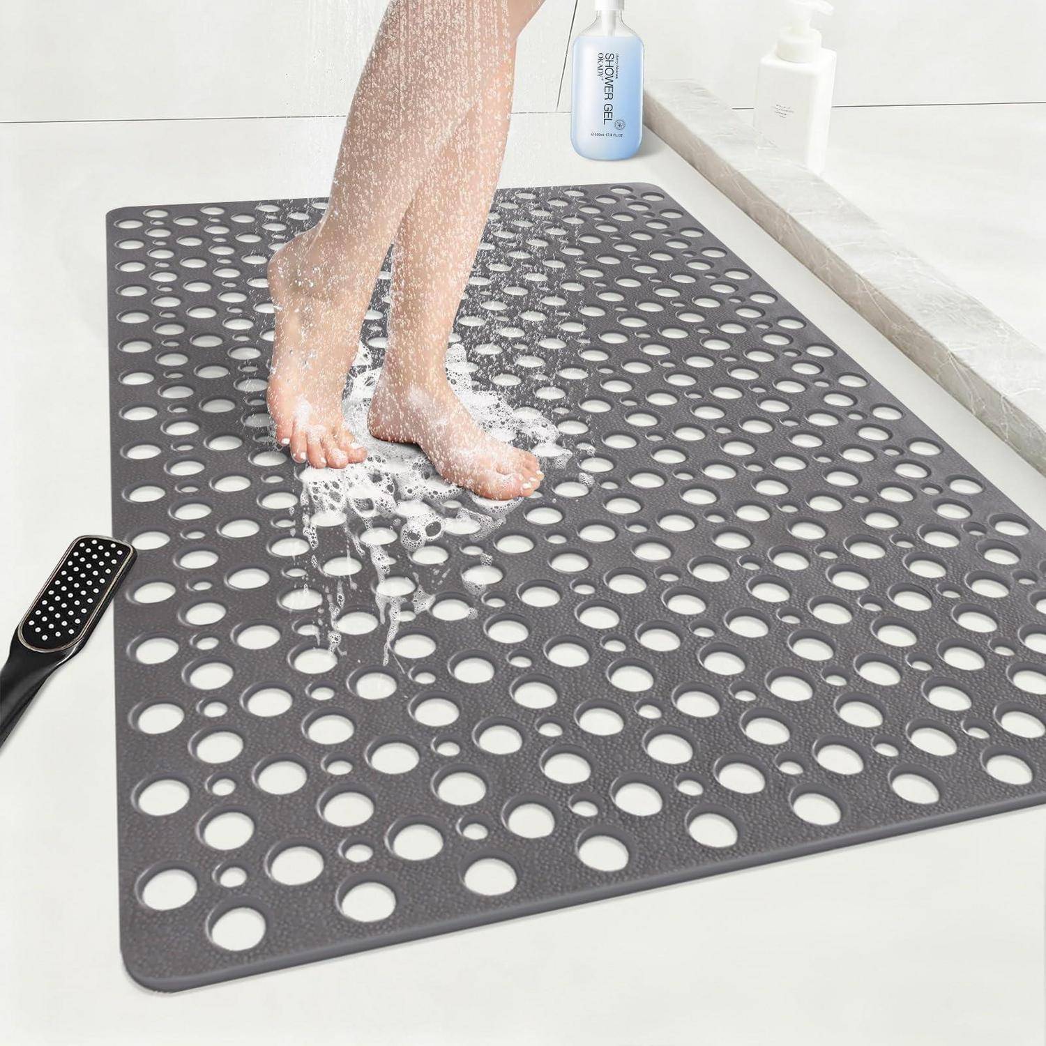 Eine Person steht auf einer perforierten grauen Duschmatte, während Wasser und Seife ihre Füße in einer Badezimmerdusche abspülen.