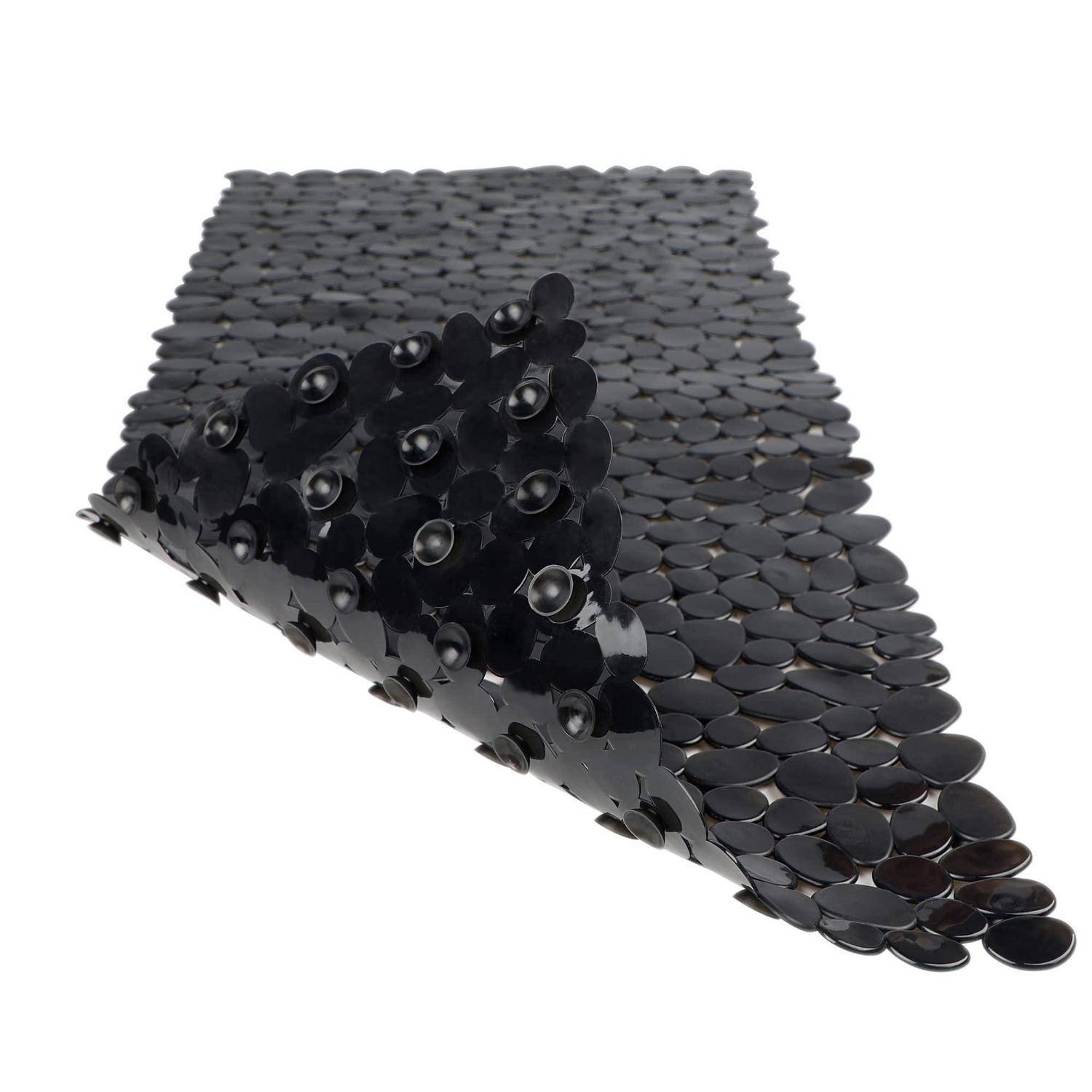Schwarzes flexibles Blatt, das mit überlappenden runden Scheiben bedeckt ist, teilweise gefaltet, um seine strukturierte, schuppenähnliche Oberfläche auf weißem Hintergrund zu zeigen.