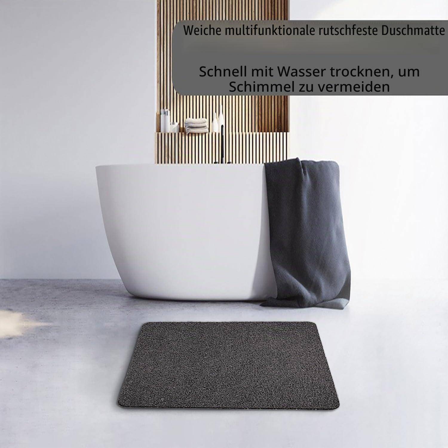 Badezimmer mit einer dunklen rutschfesten Badmatte vor einer weißen Wanne und Handtuch; der Text besagt, dass es schnell mit Wasser trocknet, um Schimmelbildung zu verhindern.