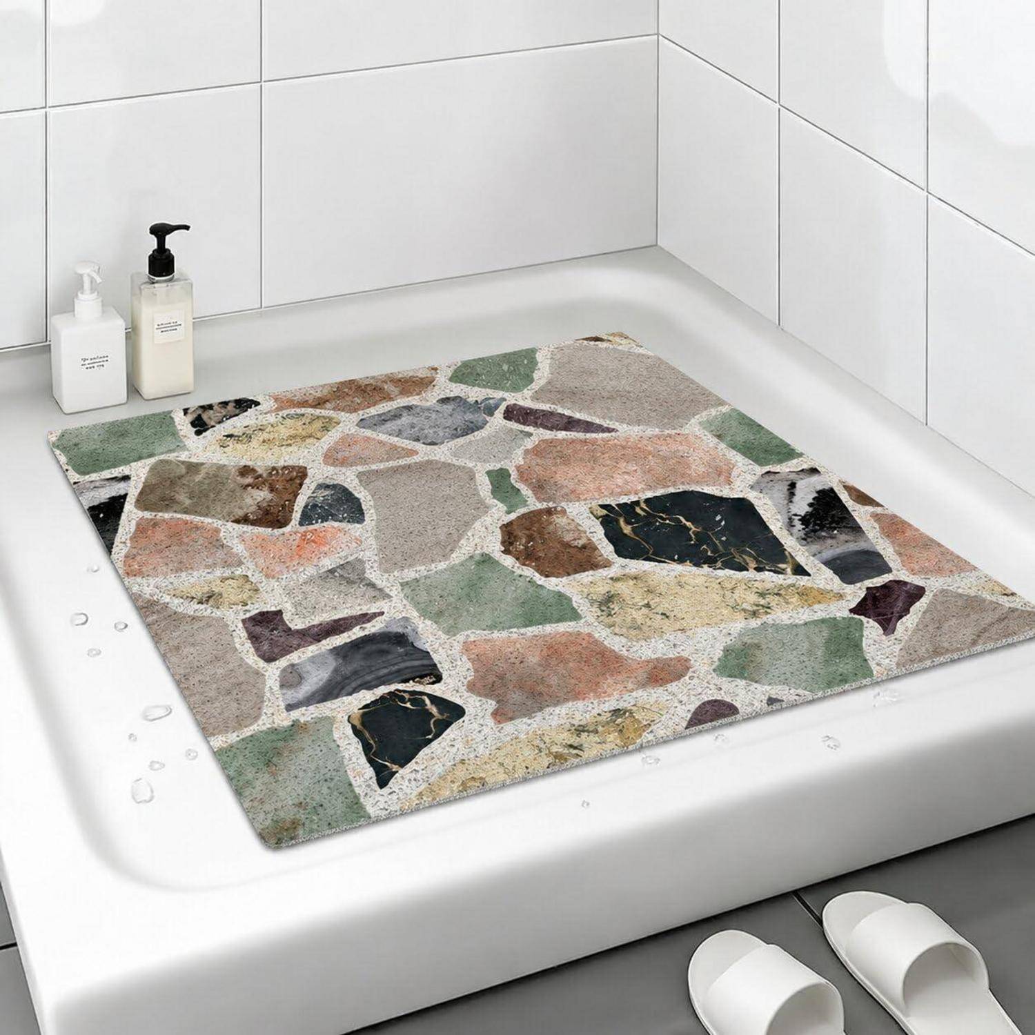 Badewannenmatte mit mehrfarbigem Steinmosaik-Muster, die auf dem Boden einer Dusche oder Badewanne platziert wird.
