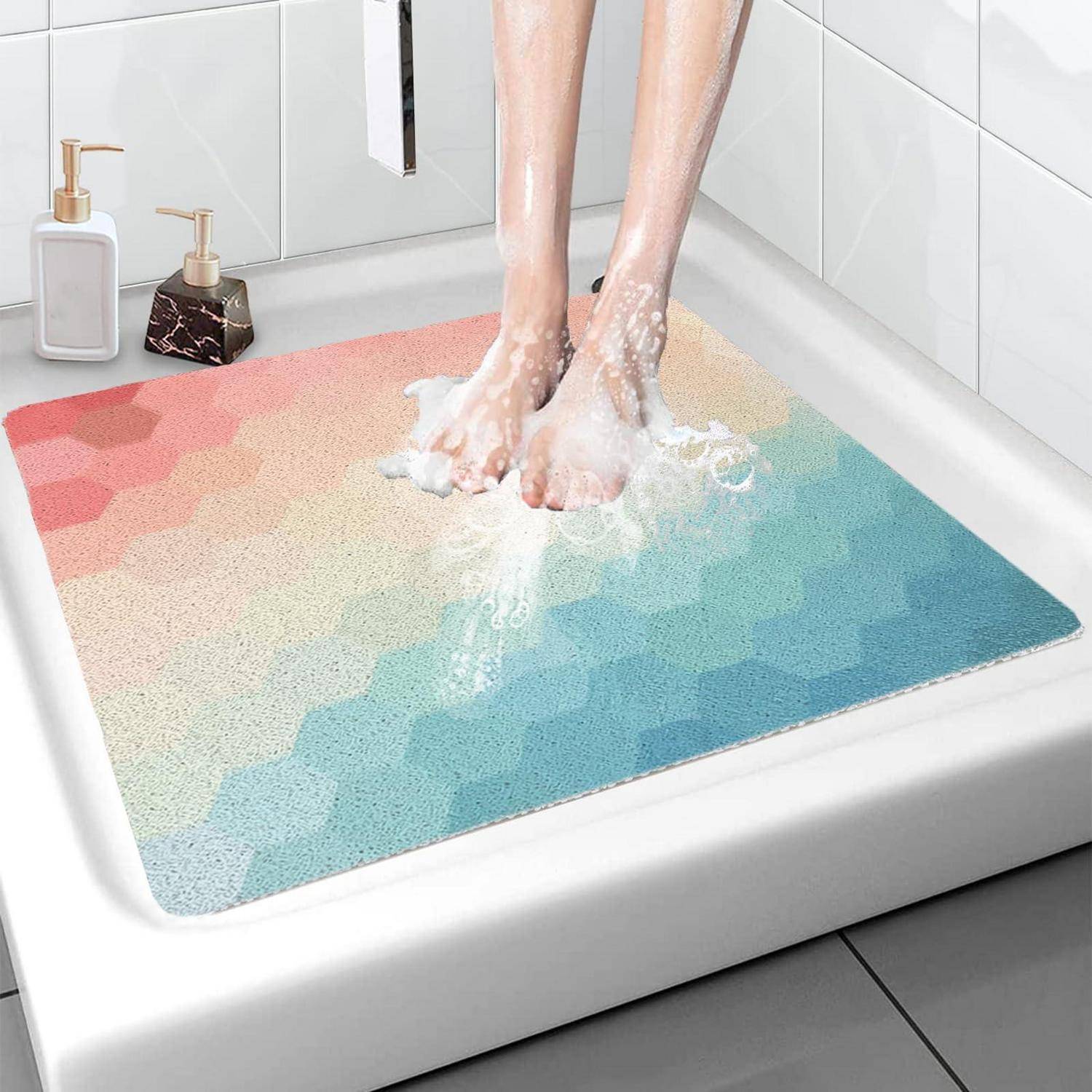Füße stehen auf einer bunten Sechseck-Muster-Badematte in einer Duschkabine, mit Seifenschaum um die Füße.