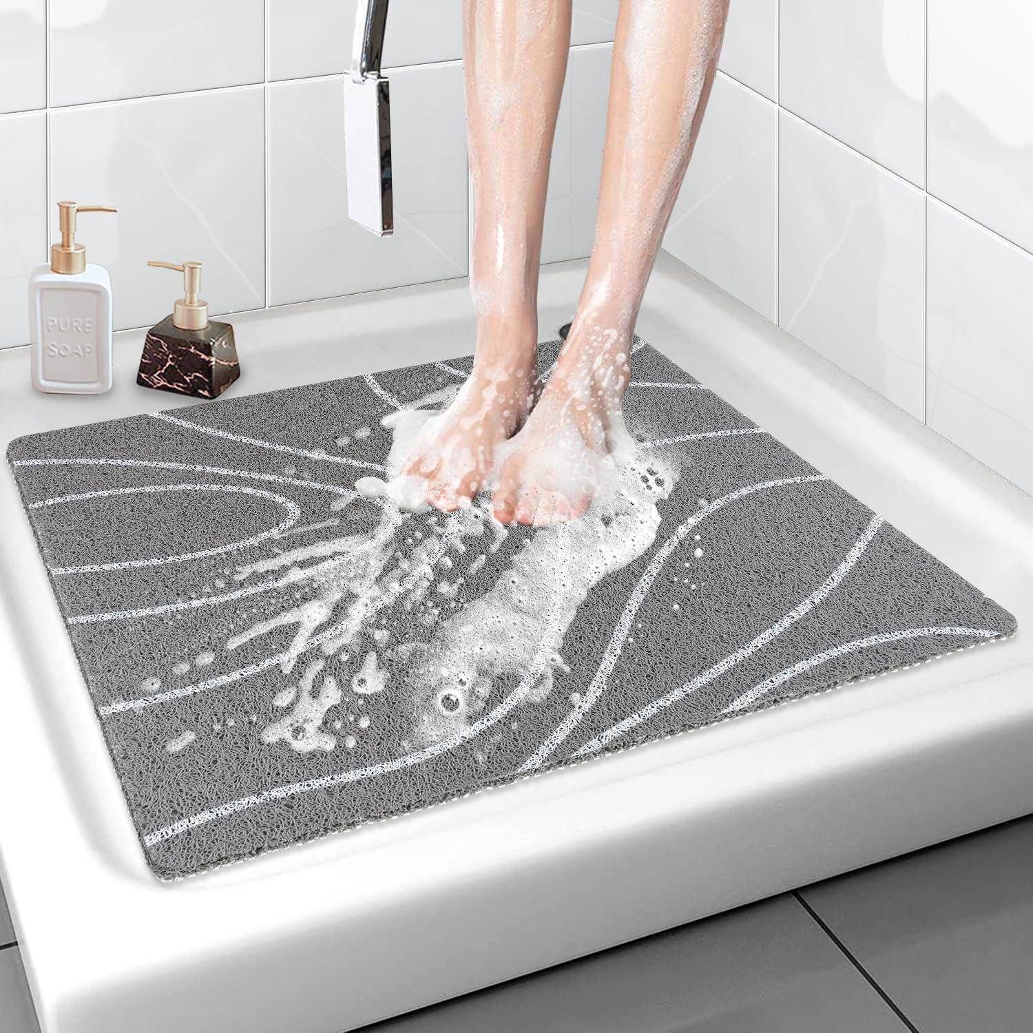 Fußwäsche auf einer grauen Badematte in einem Waschbecken oder Duschbereich, mit Seifenspendern in der Nähe, wobei eine rutschfeste, saugfähige Matte in Gebrauch gezeigt wird.