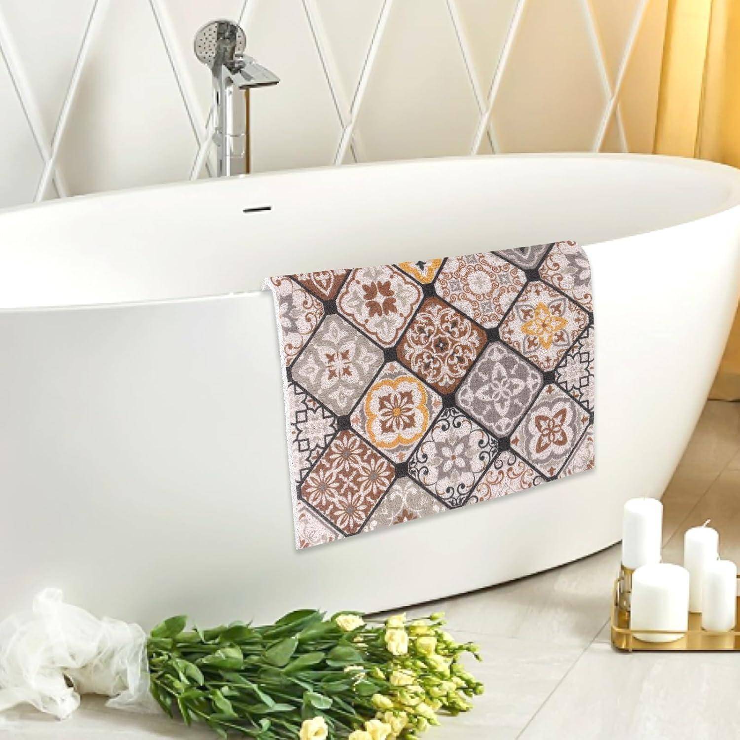 Freistehende weiße Badewanne mit gemustertem Fliesenvorhang, grünen Blumen und Kerzen in einem hellen Badezimmer.
