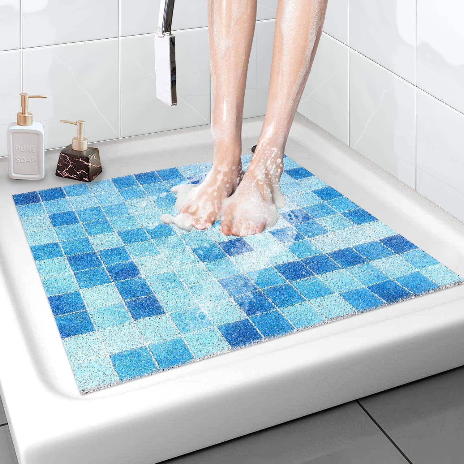 Person, der barfuß auf einer blauen karierten Badevorlage in einer Dusche steht, mit Seifenschaum an den Füßen und Beinen.