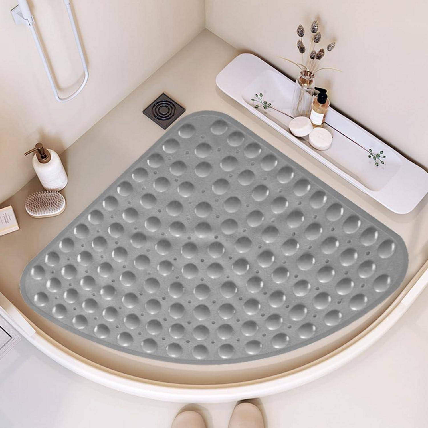 Eckige Duschablage mit grauer rutschfester Matte und Toilettenartikeln auf eingebautem Regal in einem sauberen weißen Badezimmer.