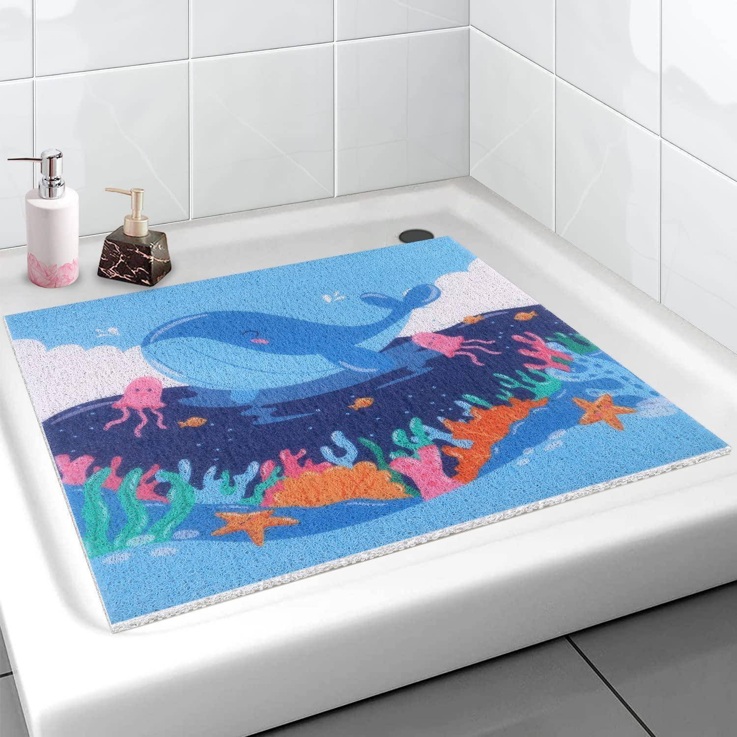 Bunte Badematte mit einem Wal und einer Unterwasserszenerie mit Korallen auf einem weißen Badewannenbrett in einem gefliesten Badezimmer.