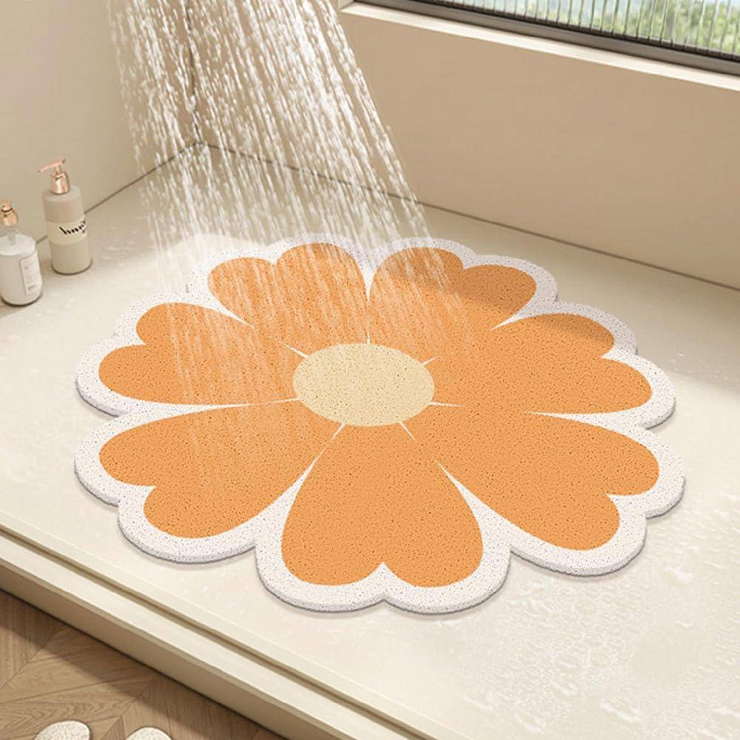 Herzförmige Blumenbadematte in Orange und Weiß unter fließendem Wasser in einem Duschbereich.