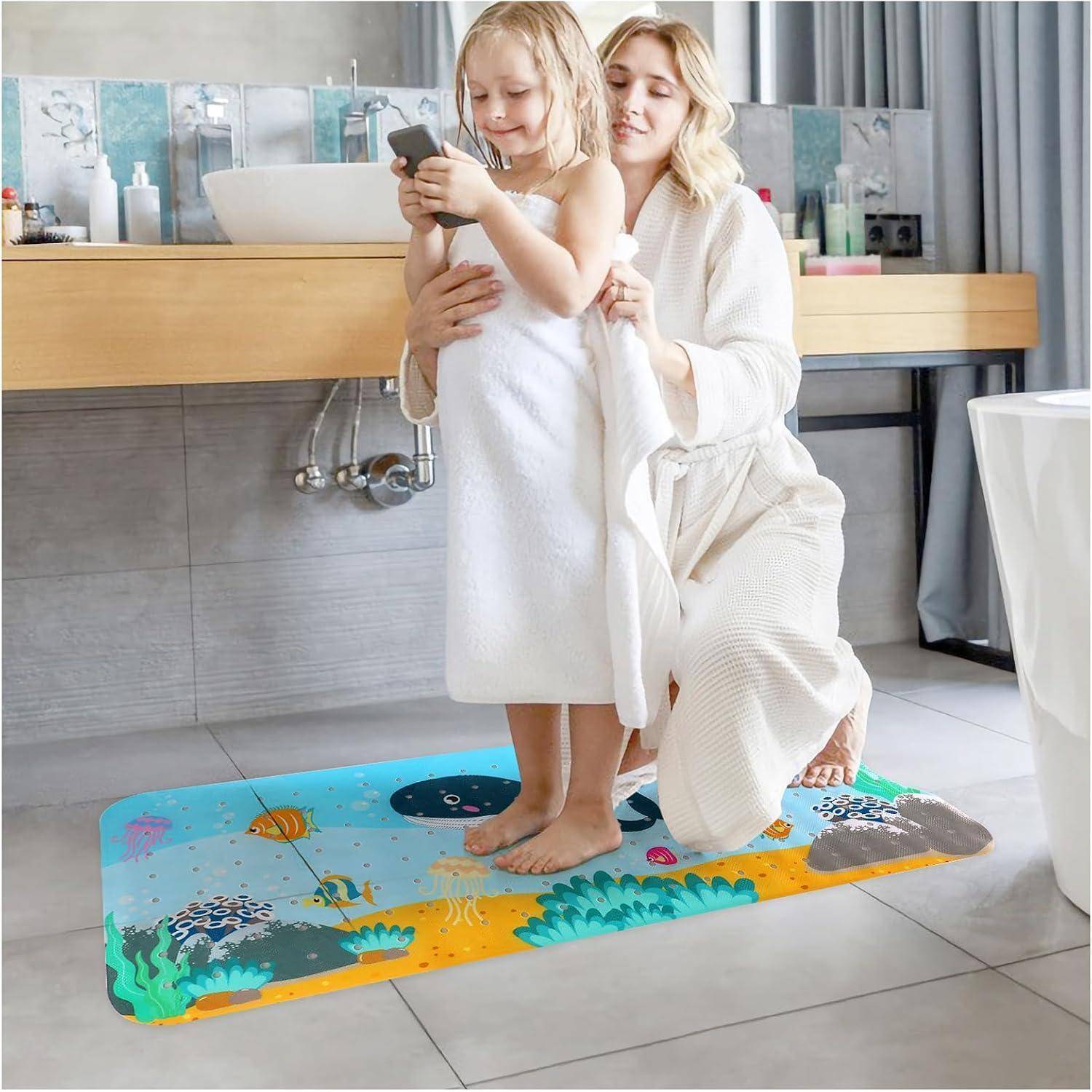 Mutter hilft einem jungen Mädchen, sich nach einem Bad im Badezimmer zu trocknen, beide sind in weiße Handtücher gewickelt und stehen auf einer farbenfrohen Matte mit Meeres-Thema.