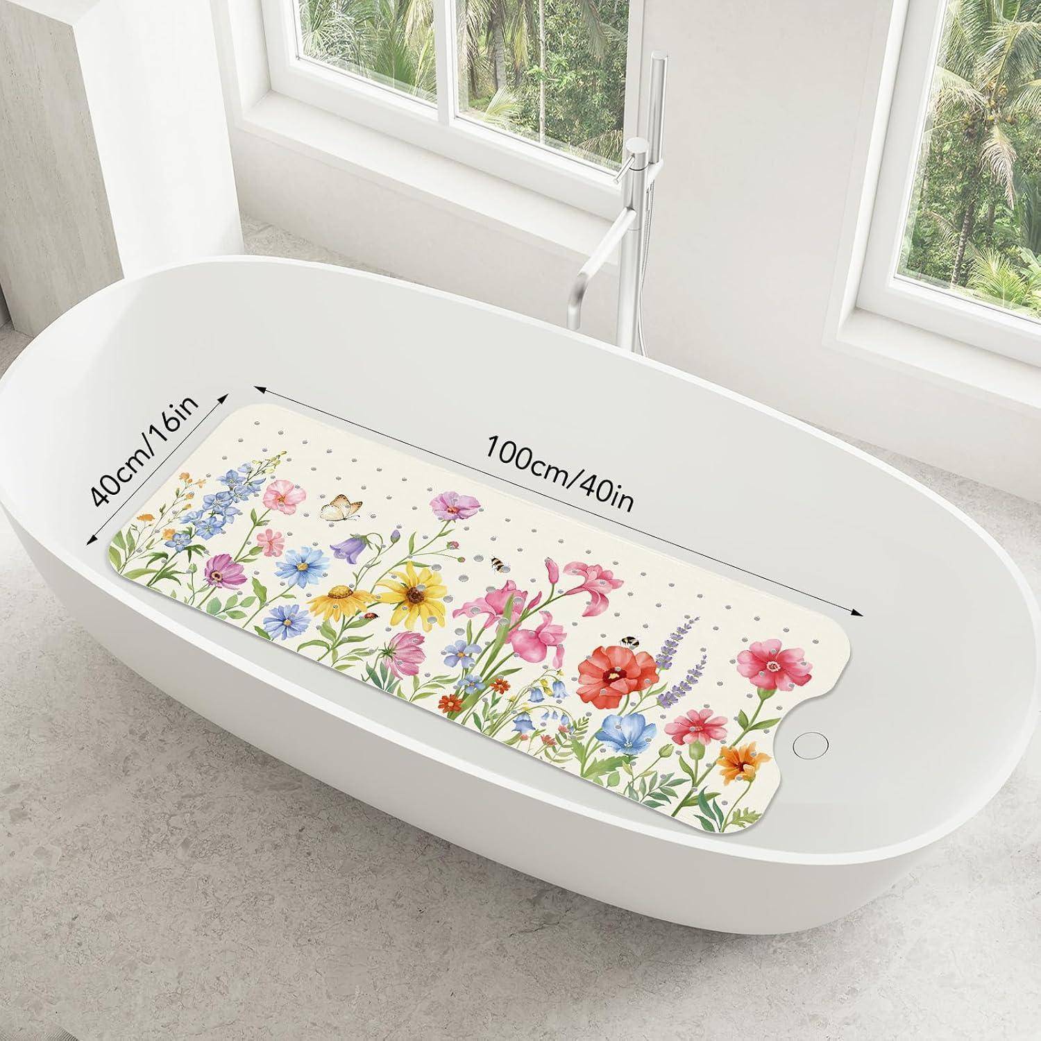 Weiße ovale Badewanne mit einer bunten Blumenbadematte, beschriftet 100 cm x 40 cm, in einem hellen Badezimmer in der Nähe eines Fensters.