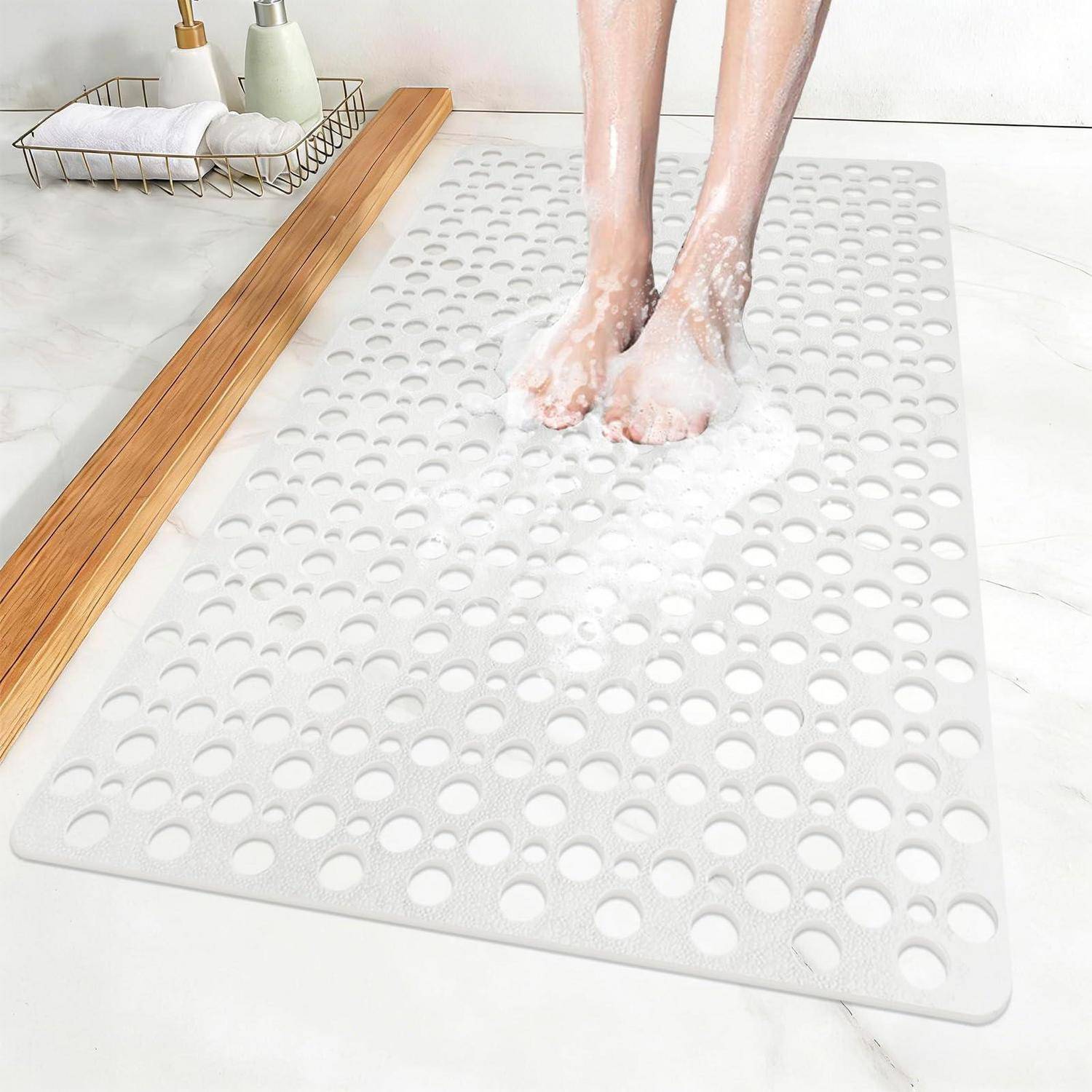 Nackte Füße stehen auf einer weißen Badewannenmatte mit Saugnäpfen, umgeben von Seifenschaum in einem sauberen Badezimmer.