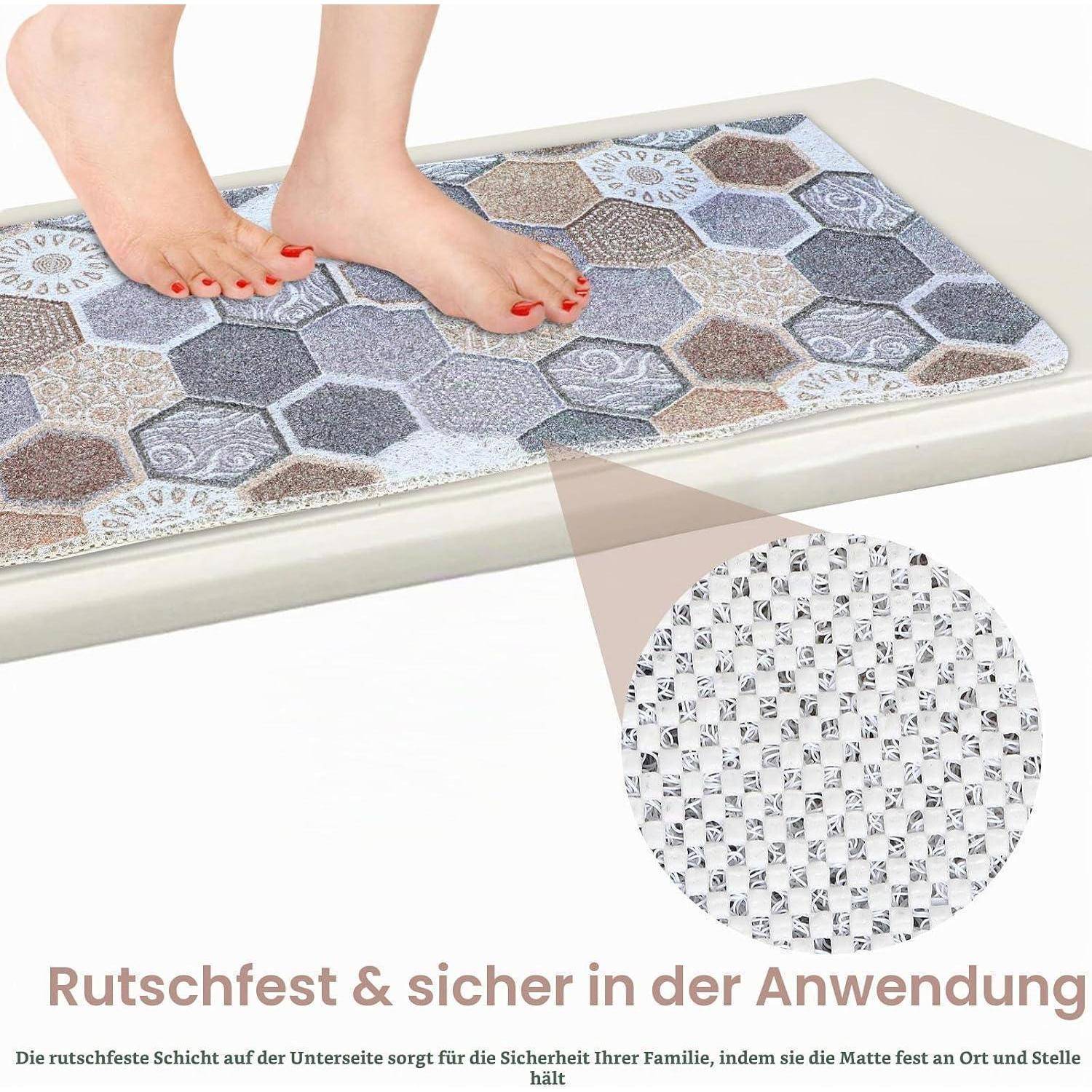 Nackte Füße stehen auf einer gemusterten rutschfesten Badmatte, die die strukturierte Unterseite zeigt; deutscher Text besagt, dass sie rutschfest und sicher zu verwenden ist.