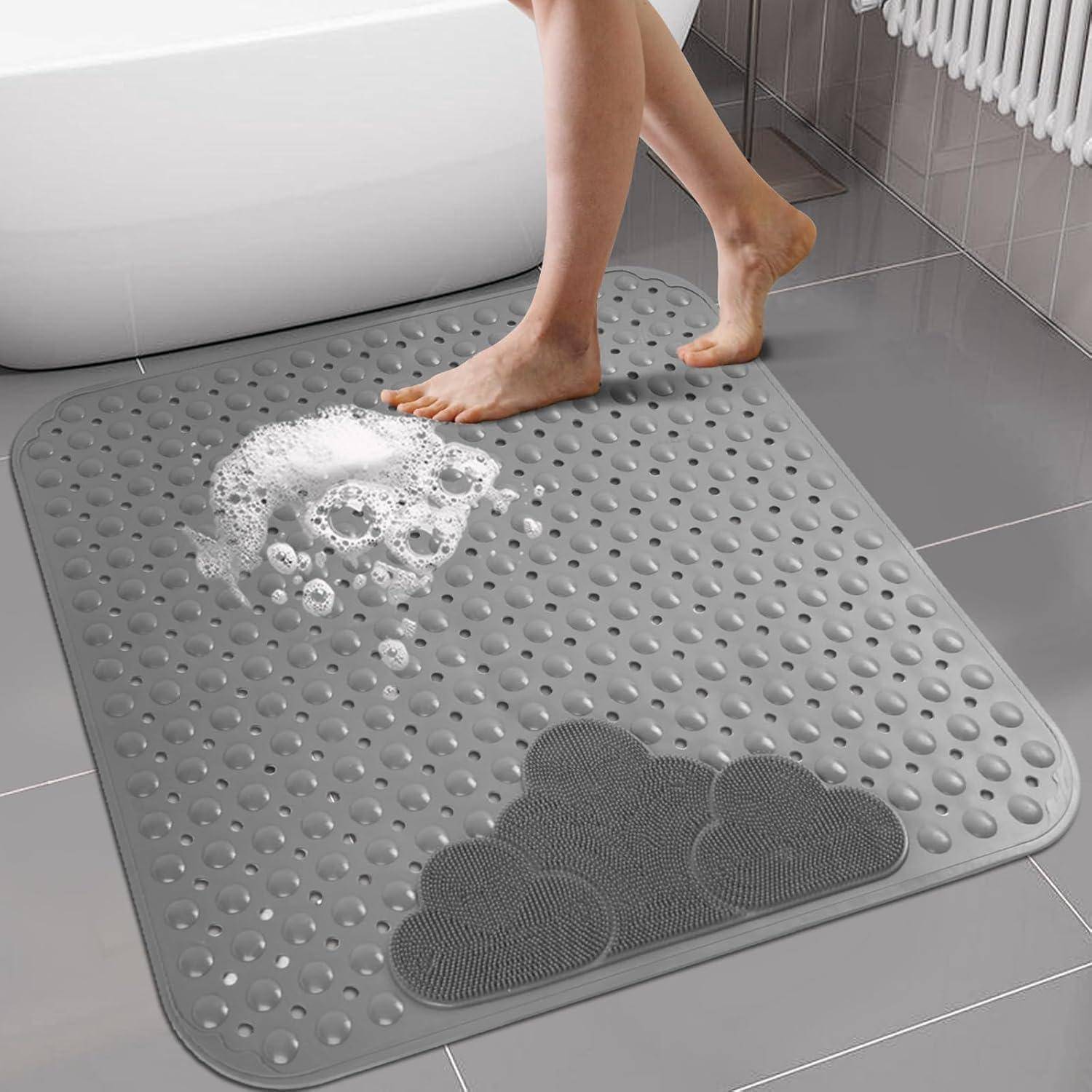 Person steigt auf eine graue Badematte im Badezimmer, mit Schaum auf der Matte in der Nähe einer Badewanne, die eine rutschfeste strukturierte Oberfläche zeigt.