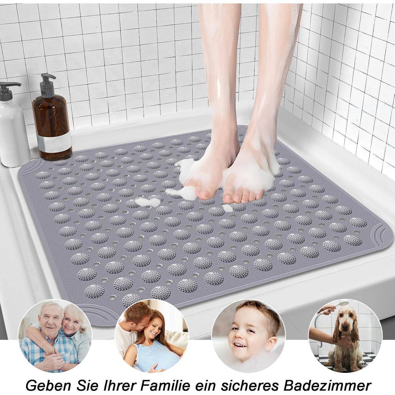 Füße stehen auf einer grauen rutschfesten Badematte in einer Badewanne, mit Flaschen in der Nähe und kleinen Familienfotos sowie deutschem Text „Geben Sie Ihrer Familie ein sicheres Badezimmer