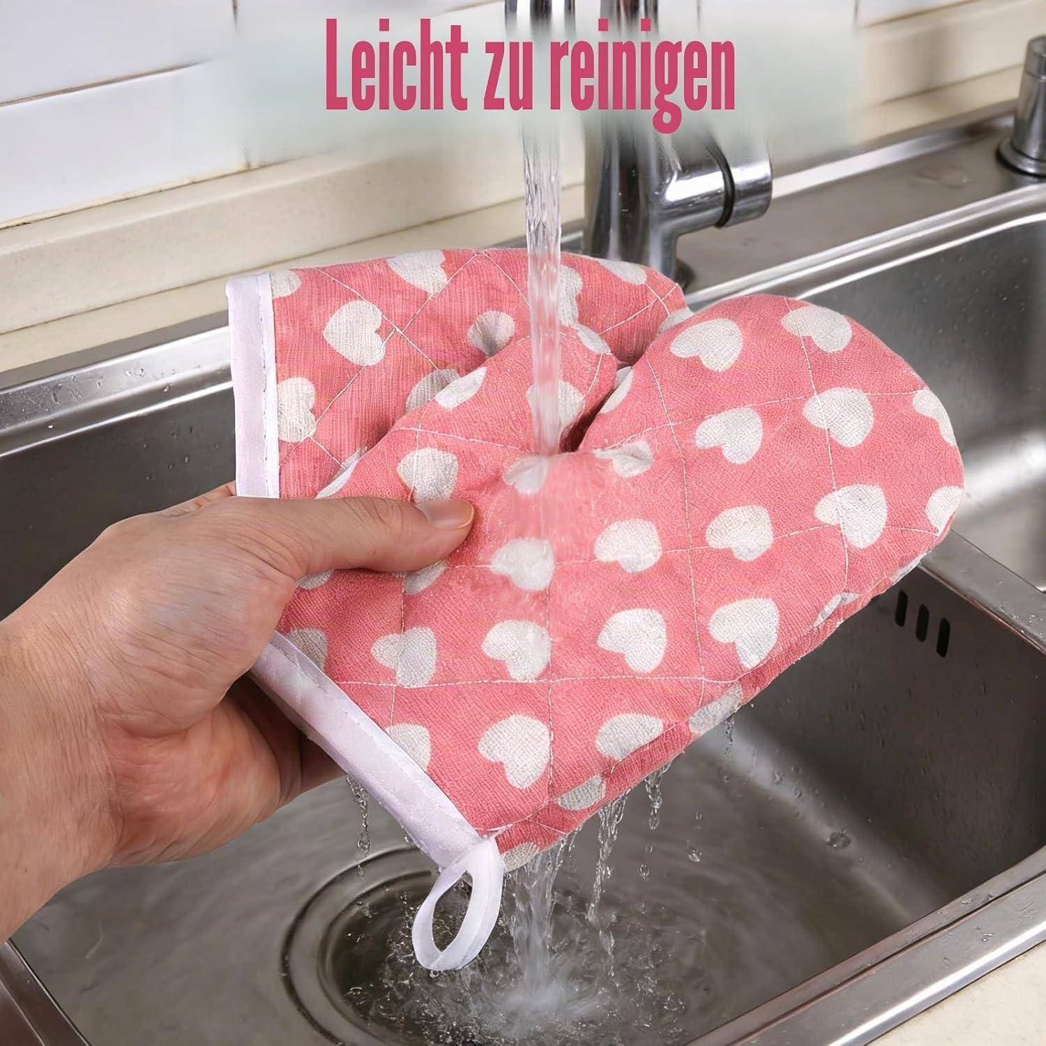 Hand rinsing a pink heart-patterned oven mitt under a kitchen faucet with the text 'Leicht zu reinigen' above.