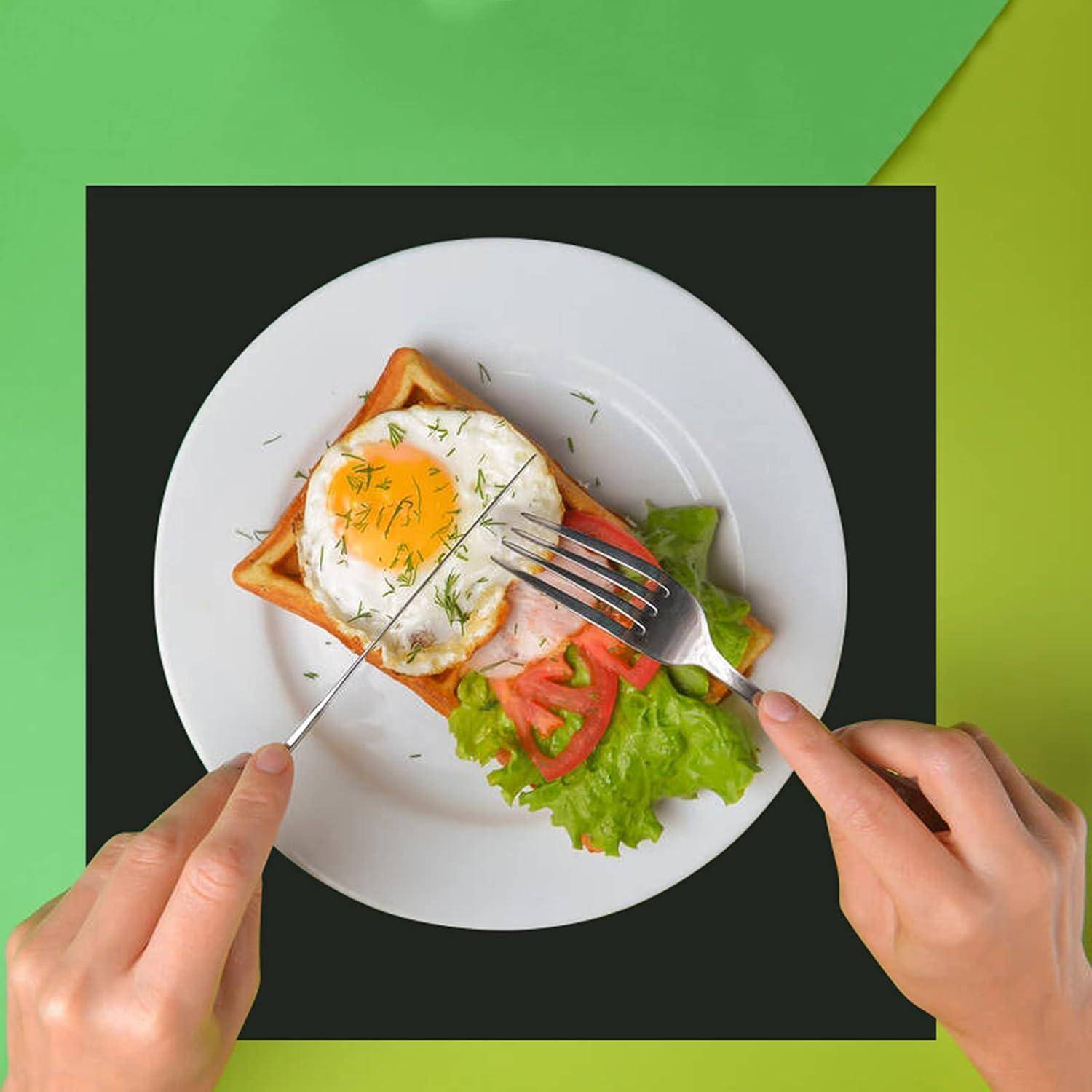 Hände schneiden ein Spiegelei-Toast-Sandwich mit Salat und Tomate auf einem weißen Teller vor grünem Hintergrund.