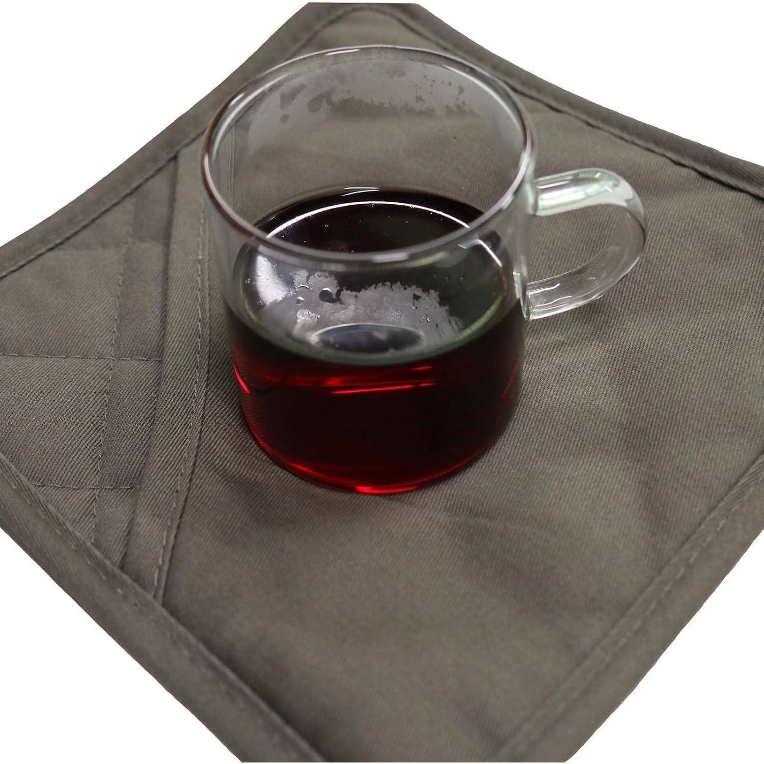 Klare Glastasse mit dunkelrotem Tee auf einem grauem gestepptem Untersetzer