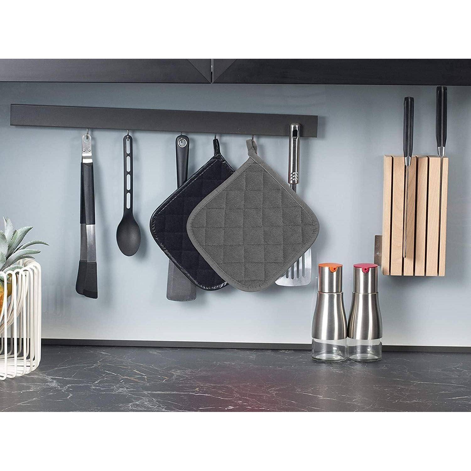 Modernes an der Küchenwand montiertes Regal mit Küchengeräten, Ofenhandschuhen, einem Spatel, Löffel, Messerblock und Öl- und Essigspender auf einer Arbeitsplatte.