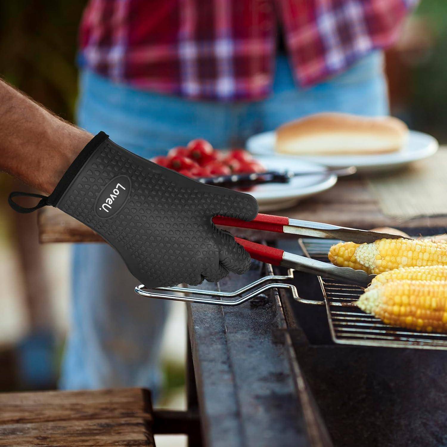 Eine Person trägt einen schwarzen hitzebeständigen Handschuh und benutzt rote Grillzangen, um Maiskolben auf einem Grill während eines Grillabends zu wenden.