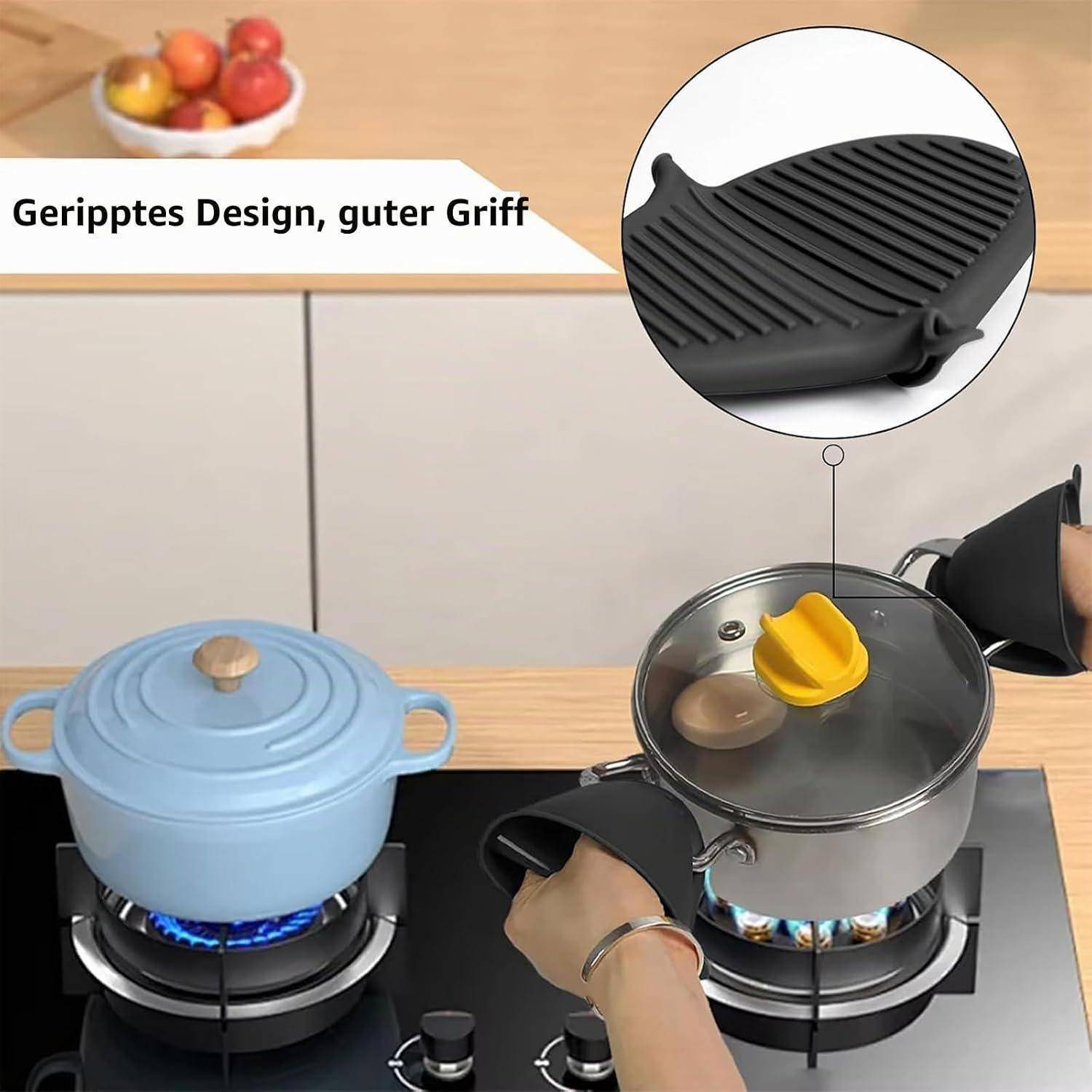 Hände, die schwarze hitzebeständige Topflappen verwenden, um einen heißen Topfdeckel anzuheben und einen Topf auf einem Gasherd zu handhaben; die Vergrößerung zeigt ein Nahaufnahme des gerippten Griffdesigns.