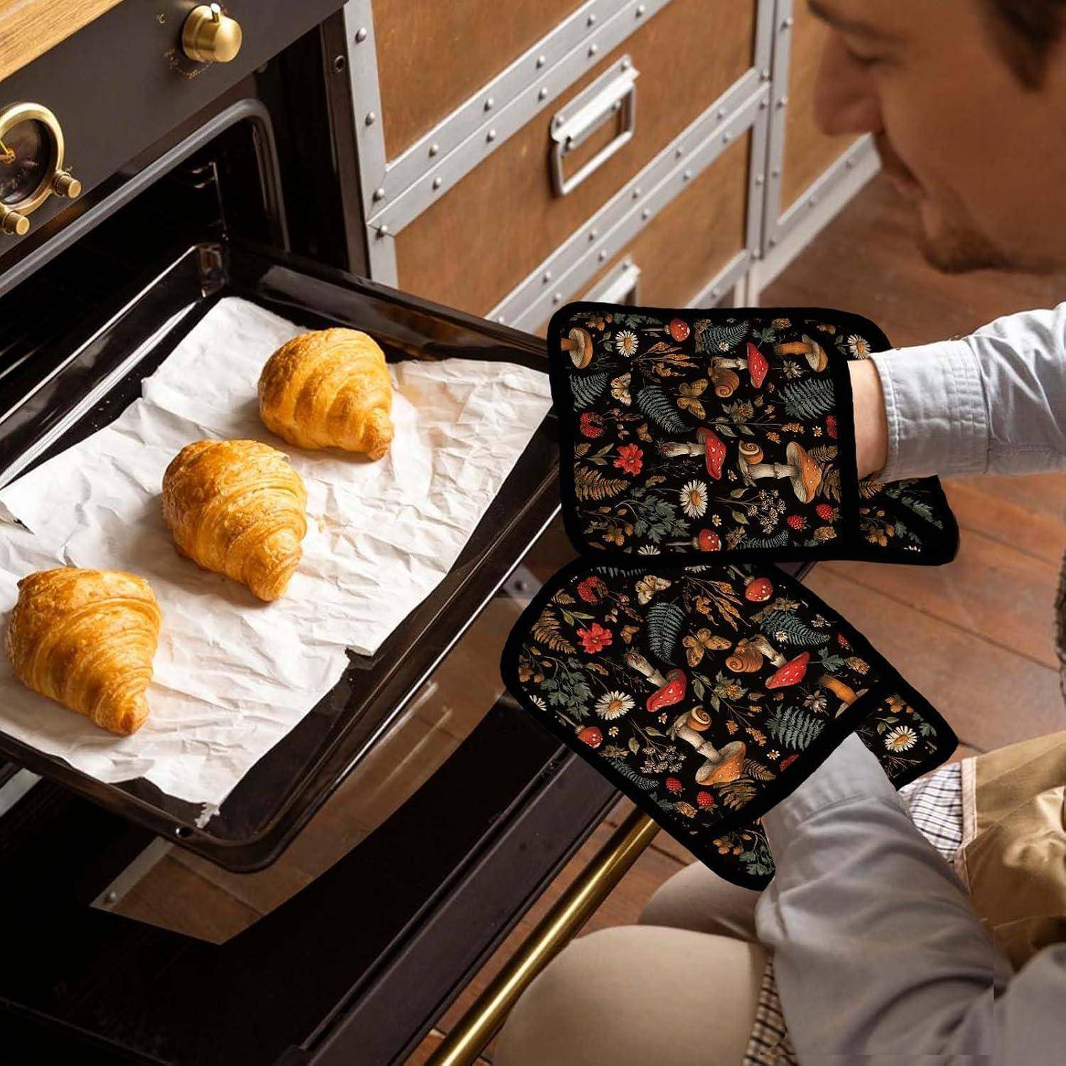 Eine Person mit floralen Ofenhandschuhen nimmt drei Croissants von einem Backblech aus dem Ofen.