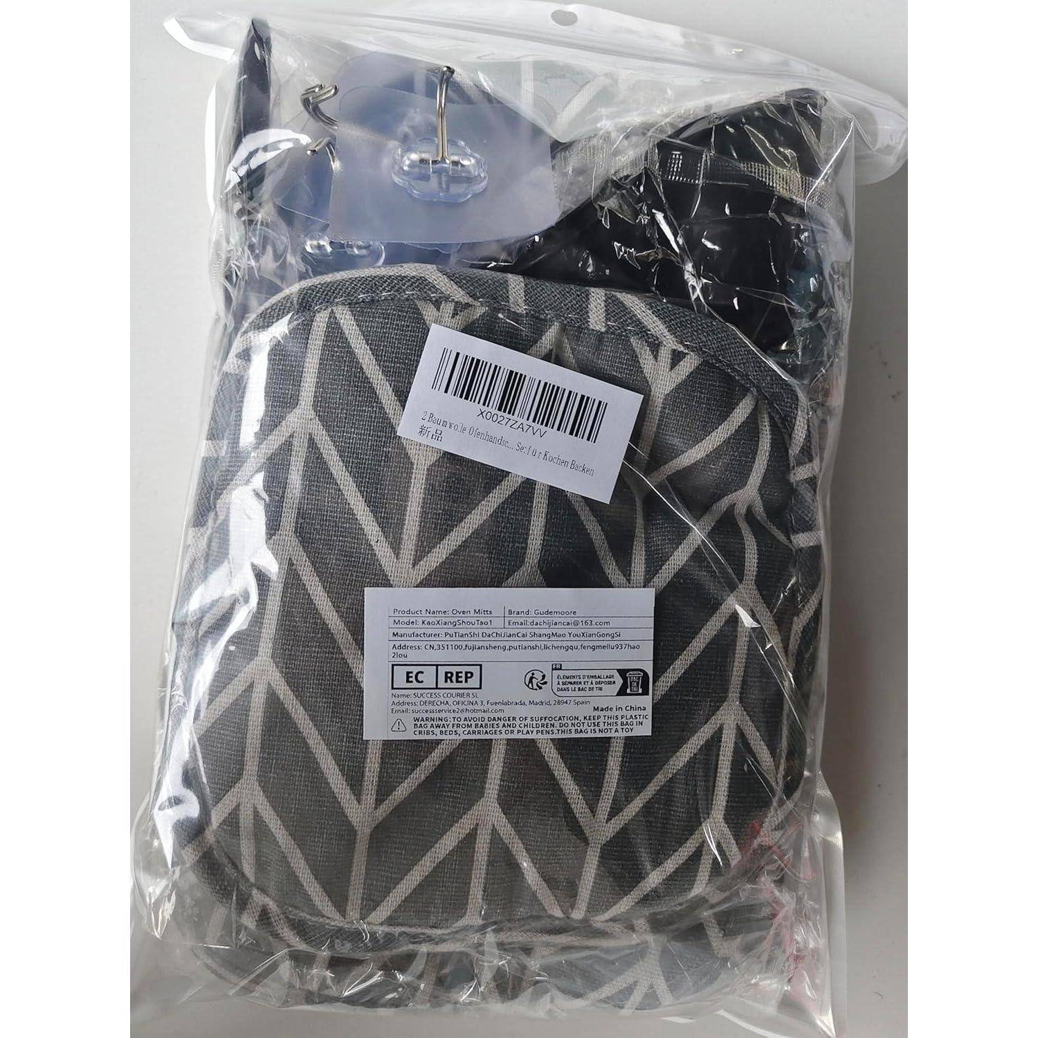 Eine gemusterte schwarz-graue Tasche, verpackt in einer durchsichtigen Kunststoffverpackung mit angebrachtem Barcode und Produktetiketten.