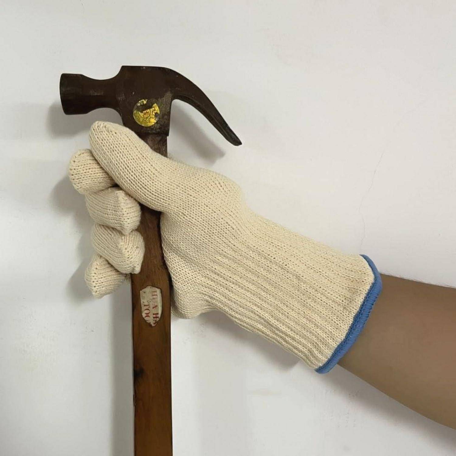 Handschuh-behandelte Hand, die einen Krallenhammer aufrecht gegen einen einfachen hellen Hintergrund hält.