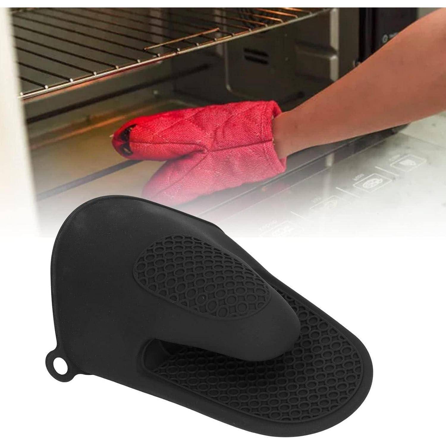 Schwarzer Silikonofenhandschuh mit einer rothandschuhtragenden Hand, die im Hintergrund in einen Ofen greift, zeigt Hitzeschutz beim Kochen.